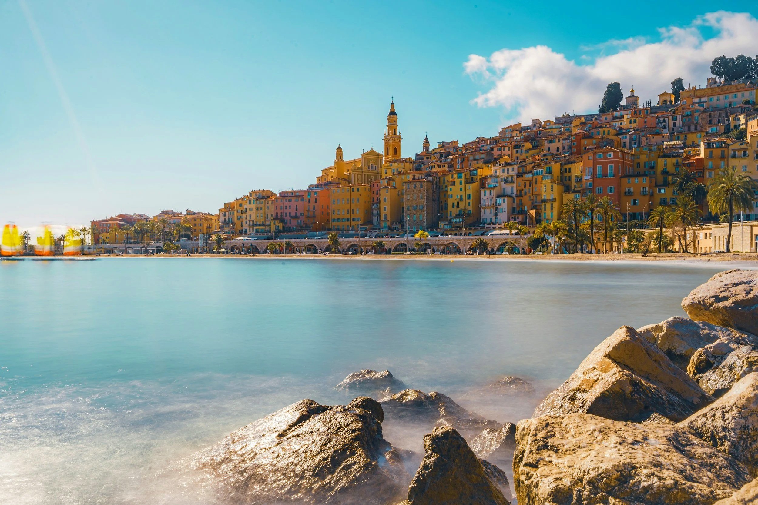 Vernazza, un pintoresco pueblo en la costa de Italia, con colores vibrantes en sus edificios y una playa tranquila con rocas en primer plano.