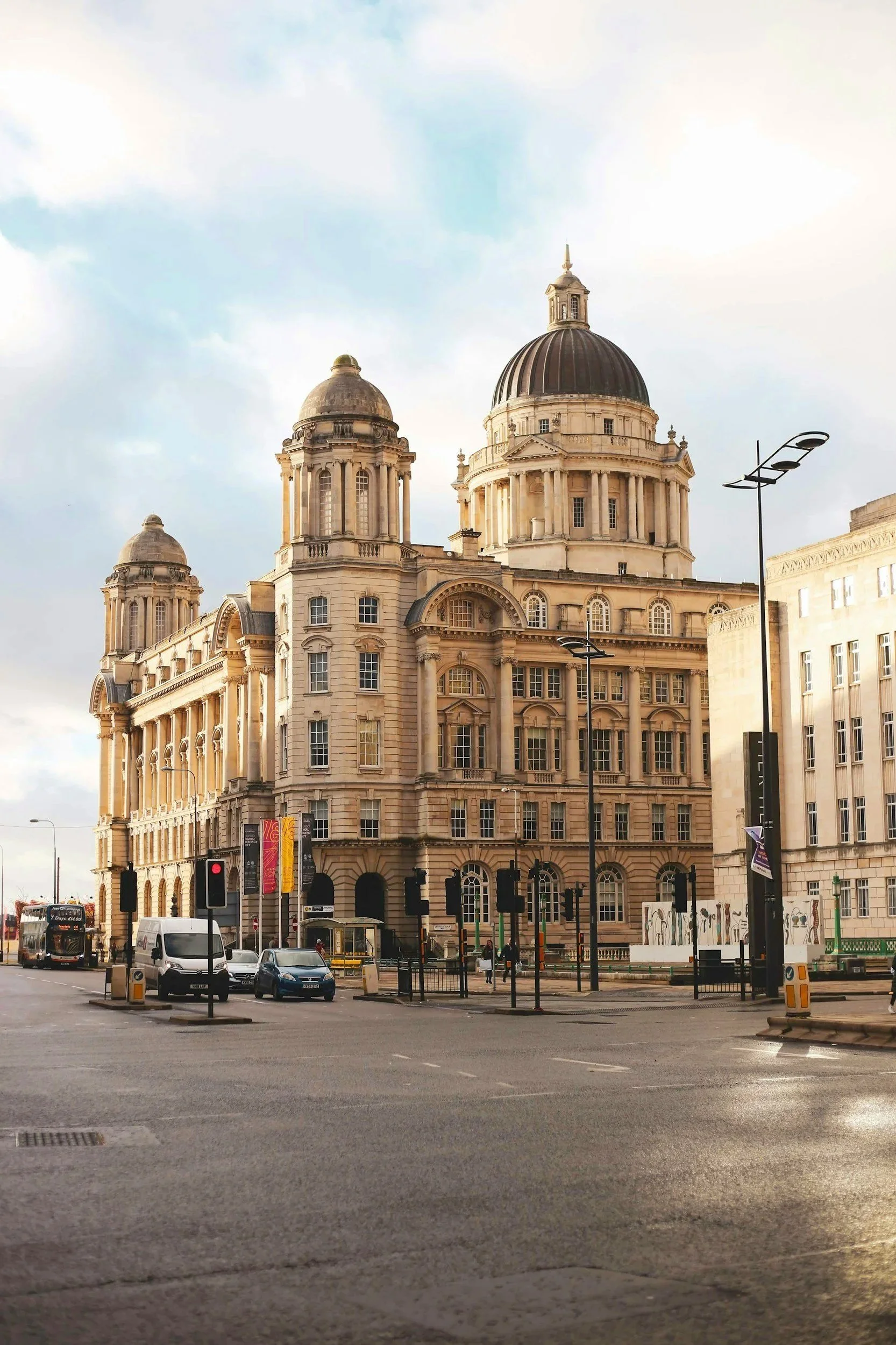 Edificio histórico con cúpulas y arquitectura clásica en una calle urbana con tráfico y semáforos.