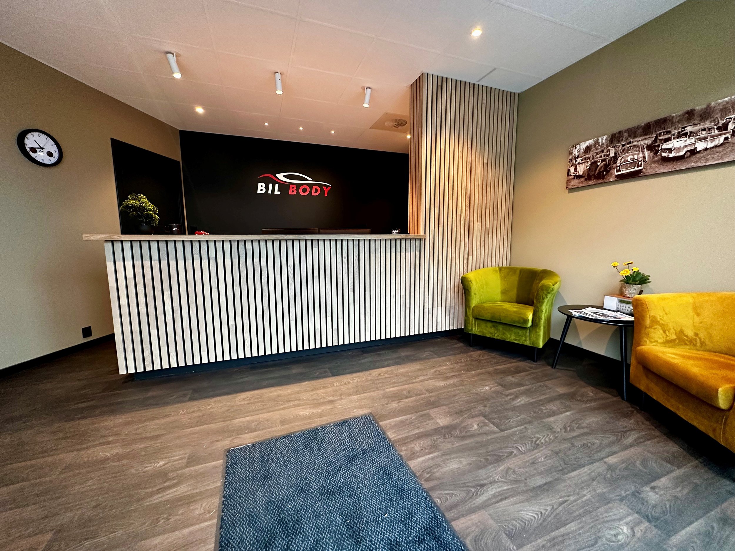 To unge kvinner sitter i bagasjerommet på en bil, ler og deler et øyeblikk av glede, med grønne omgivelser i bakgrunnen.