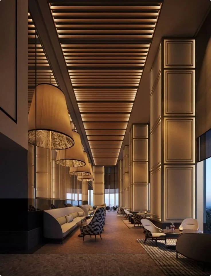 Elegant hotel lobby of Janu Tokyo with high ceiling, large hanging lamps, comfortable seating, and floor-to-ceiling windows showing an outdoor view.