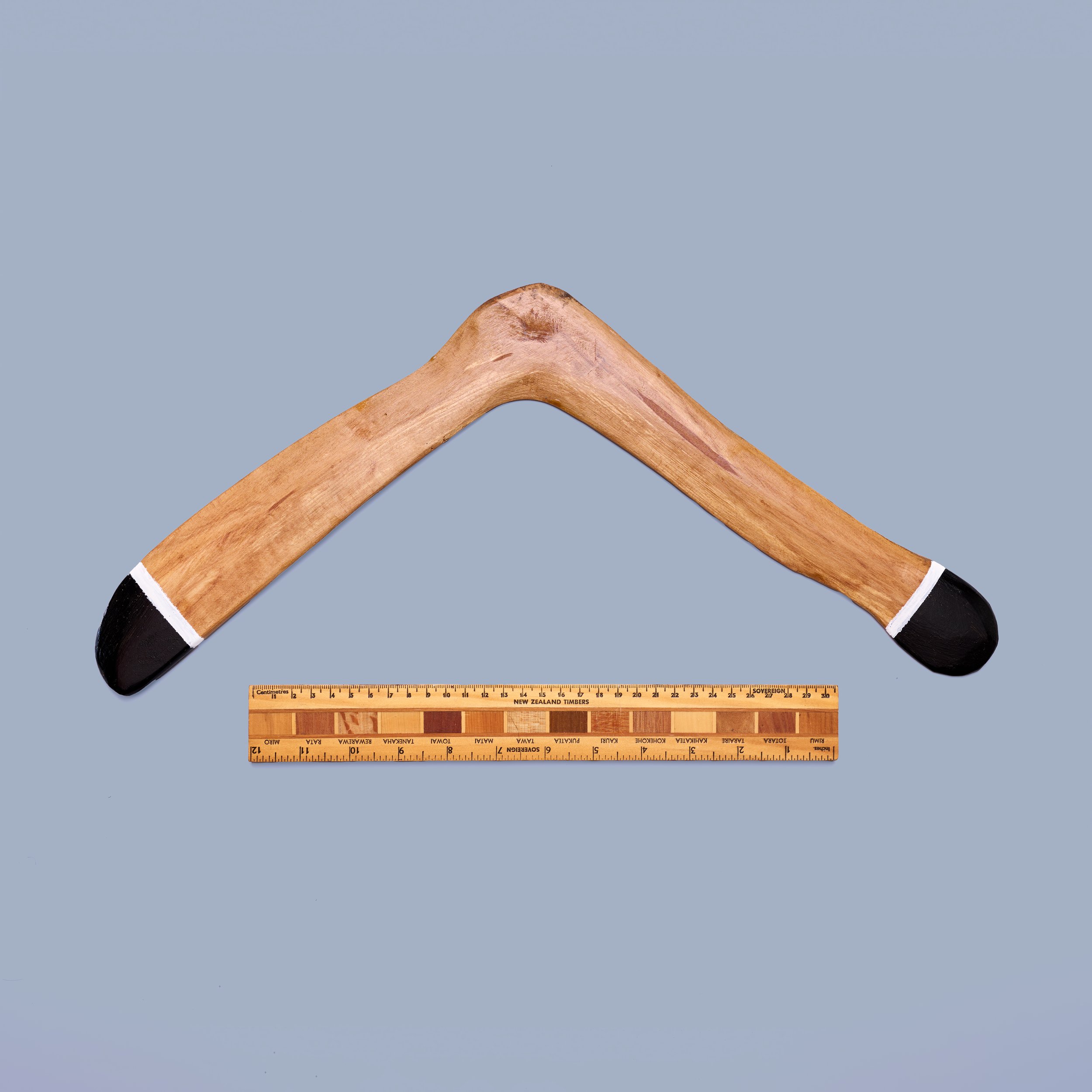 A wooden coat hanger, a wooden ruler, and a wooden cribbage board on a light blue background.