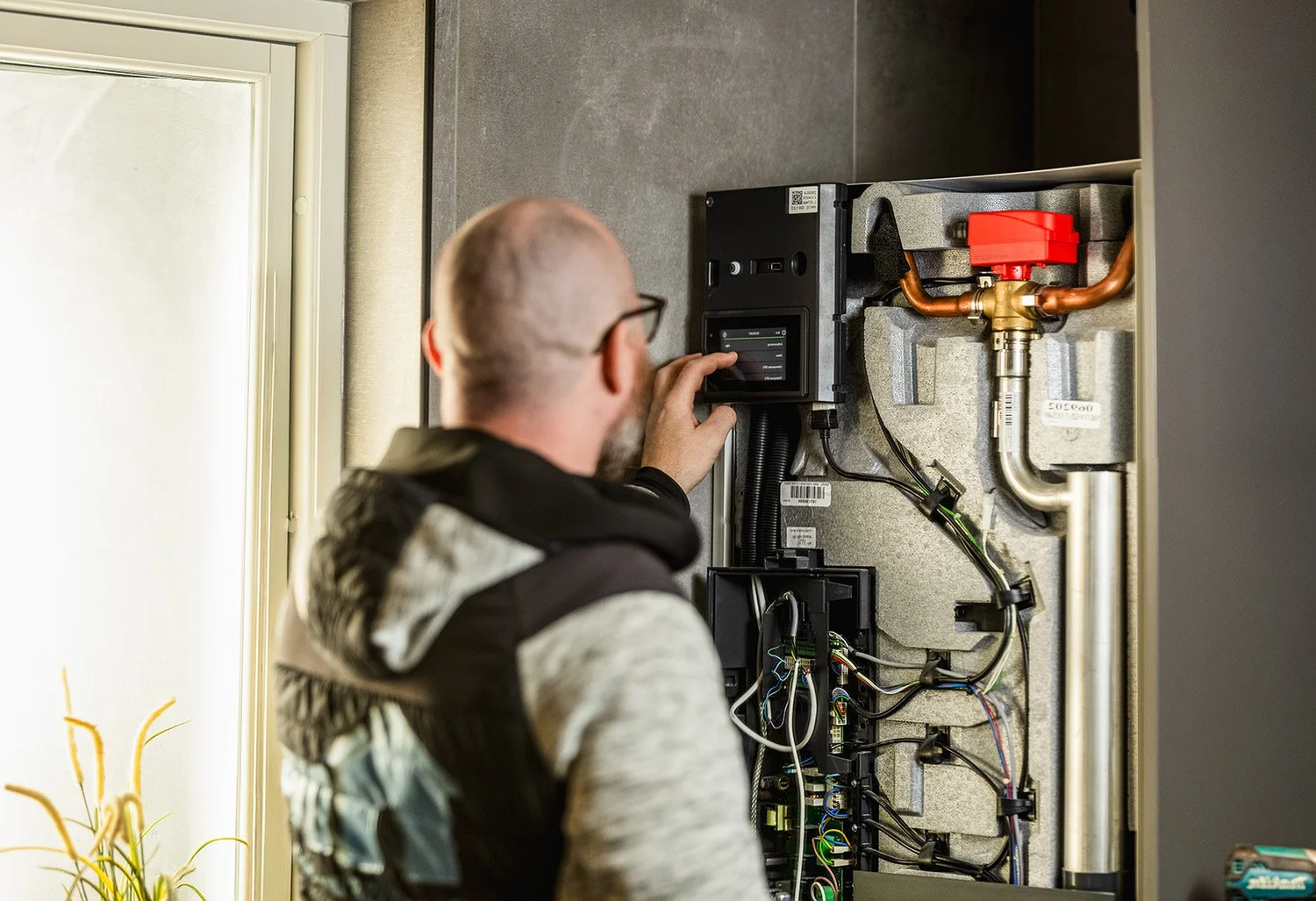 En man tittar på en digital skärm på en teknisk utrustning som är installerad på en vägg.