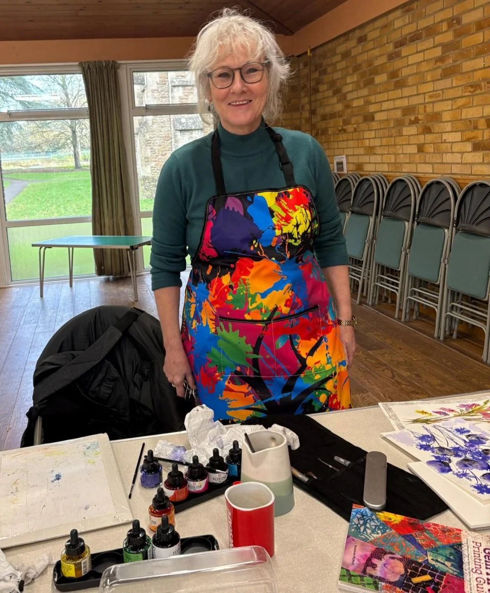 Collection of small landscape paintings on miniature easels on floral tablecloth.