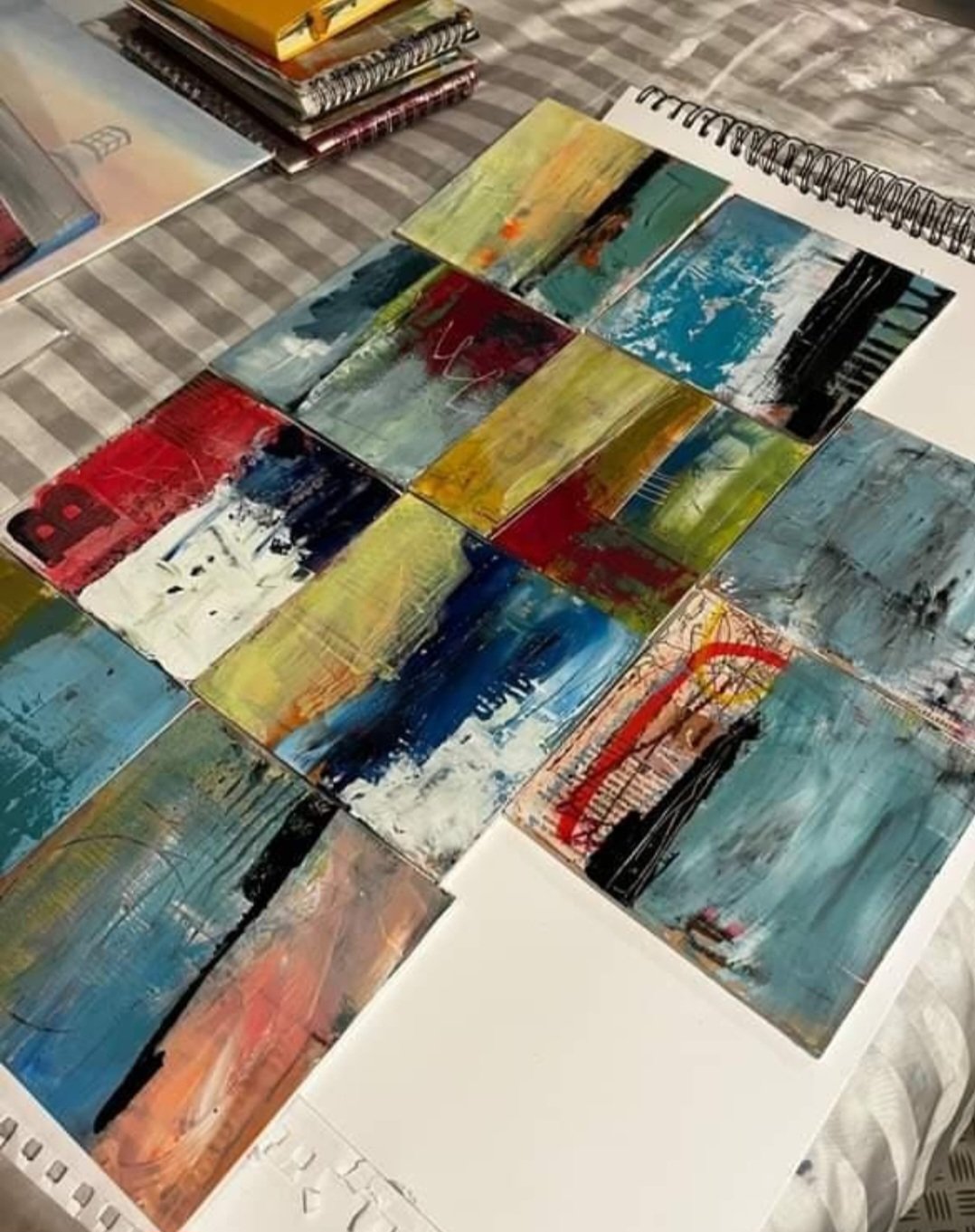 Collection of small abstract landscape paintings with vibrant colors arranged on a table.