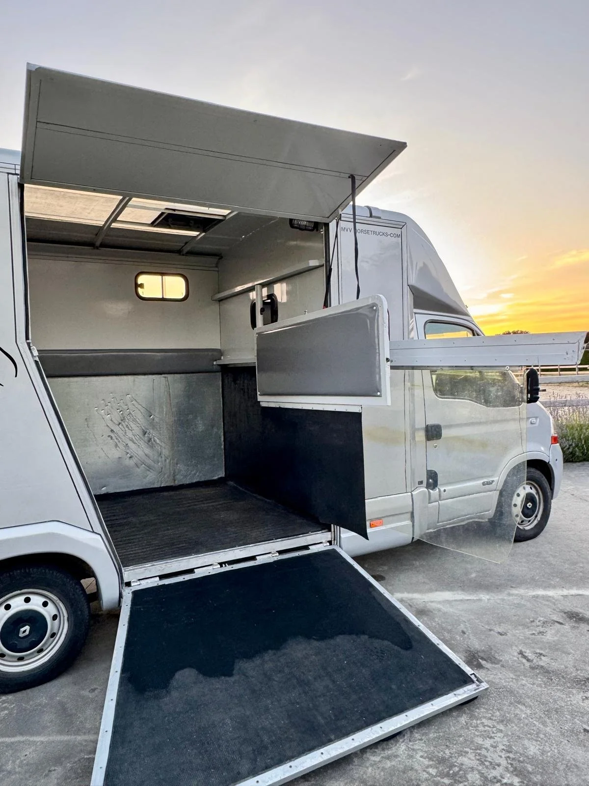 Paardencamionette met open zijdeuren, klaar voor gebruik, geparkeerd bij zonsondergang.
