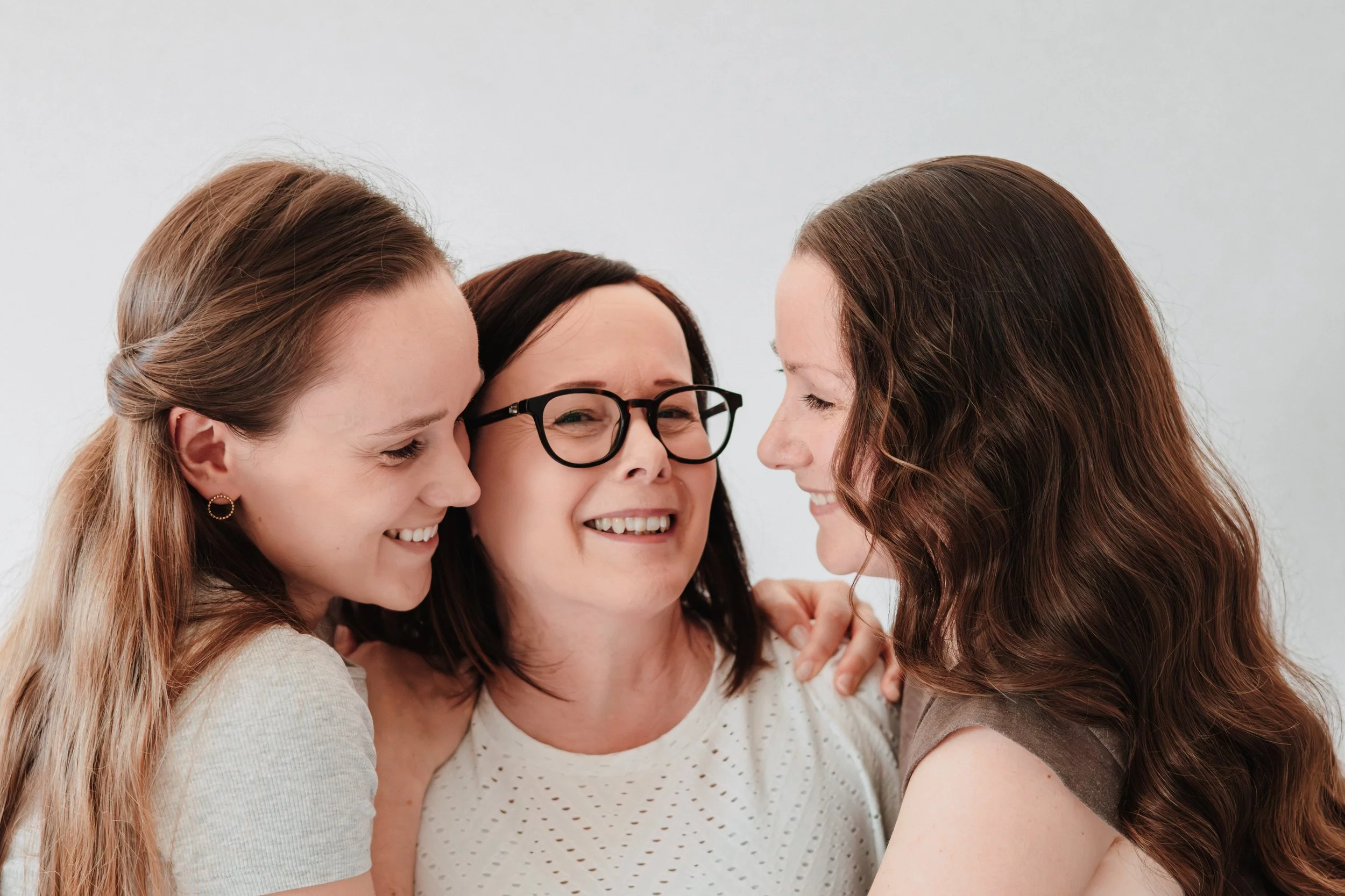 Vier Frauen umarmen sich und lachen in enger Freundschaft.