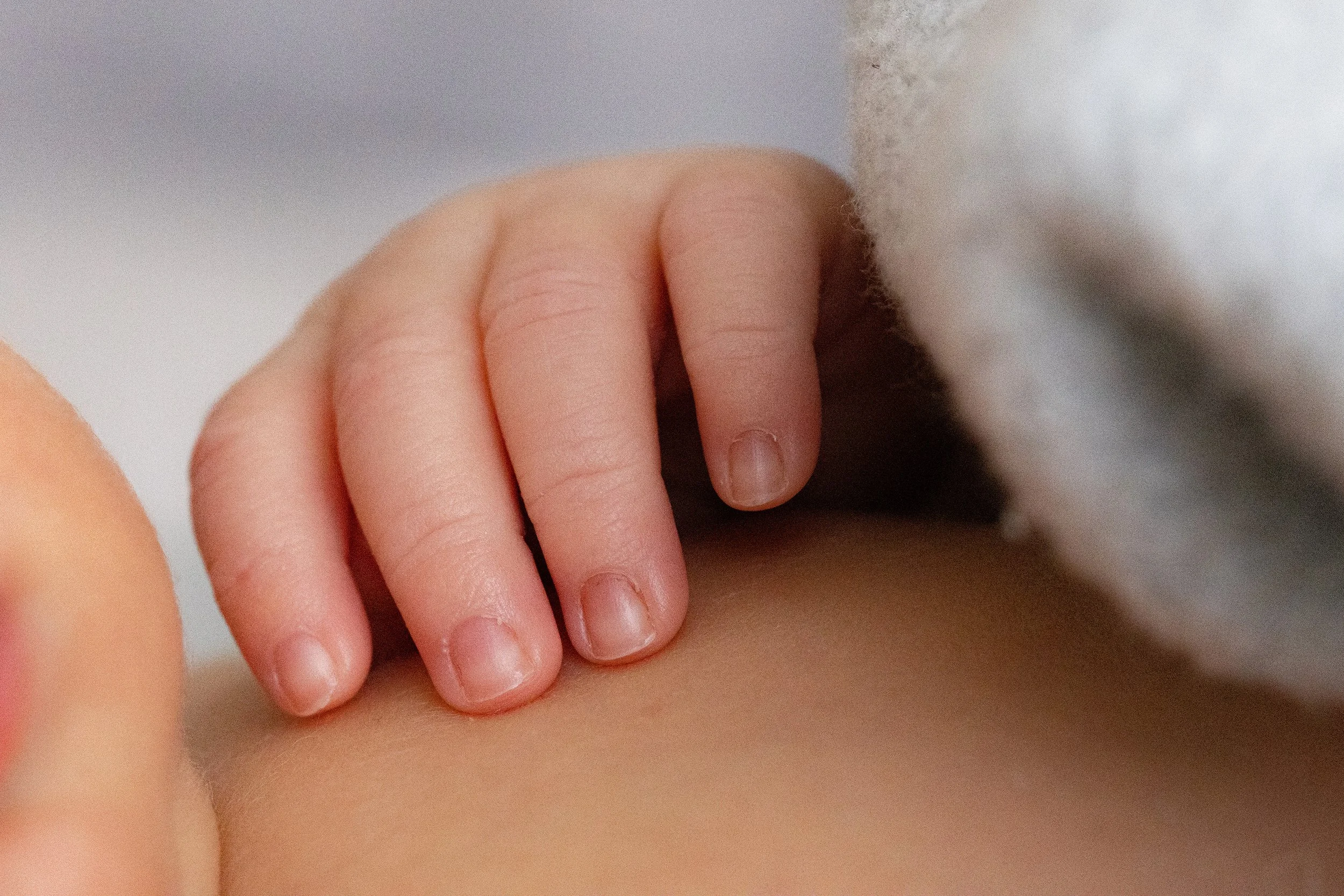Nahaufnahme einer Kinderhand, die auf der Haut eines anderen Menschen liegt.