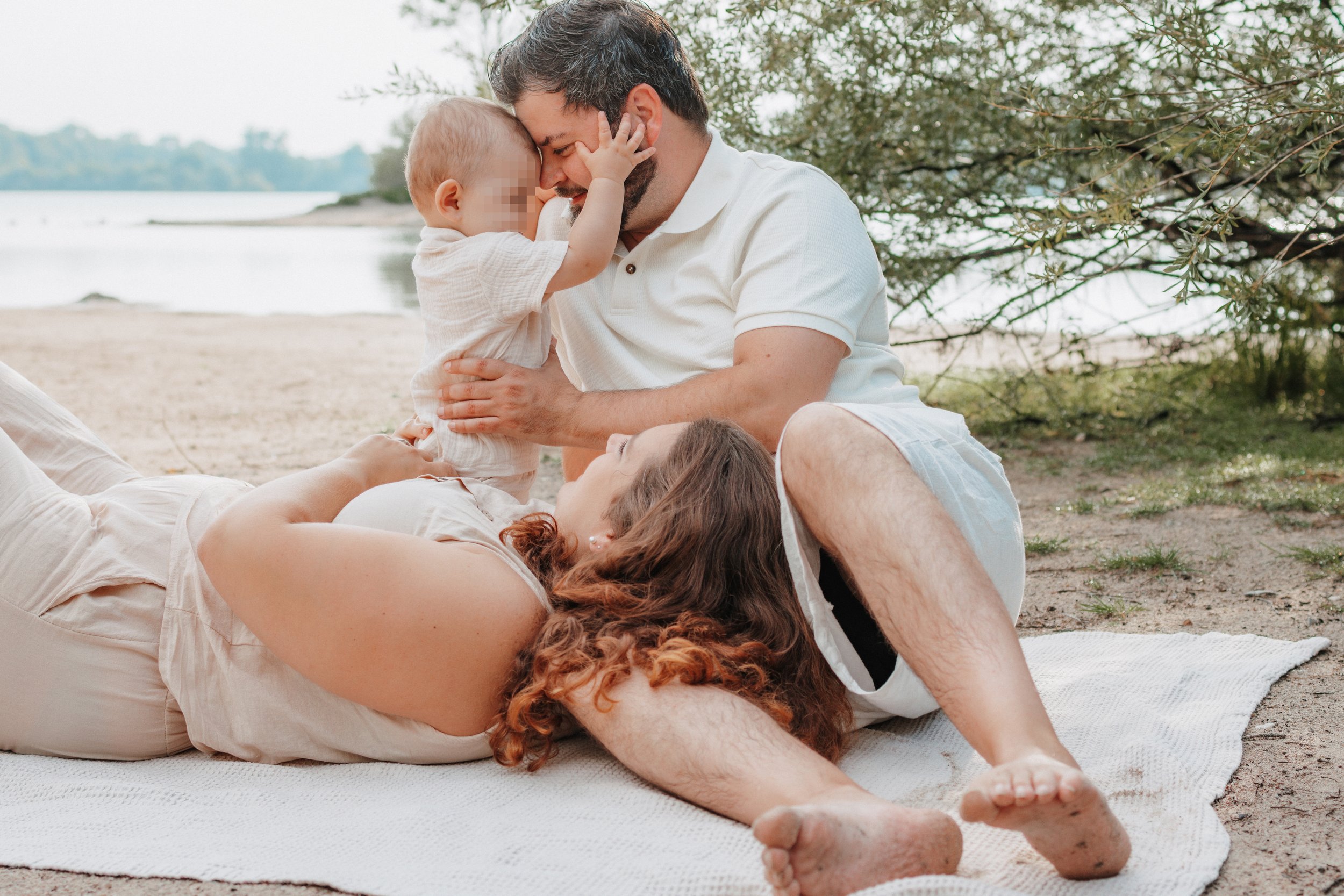 Familie mit Kind am Strand, malt sich gemeinsam, lachend und glücklich.