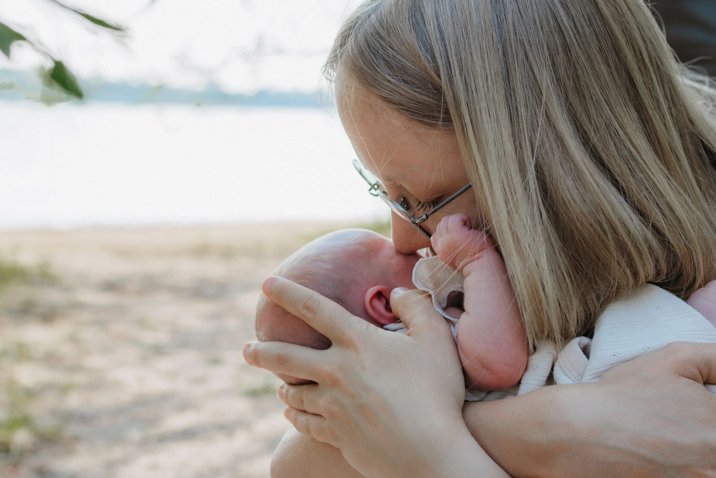 Eine Frau hält ein neugeborenes Baby im Arm und küsst es zärtlich.