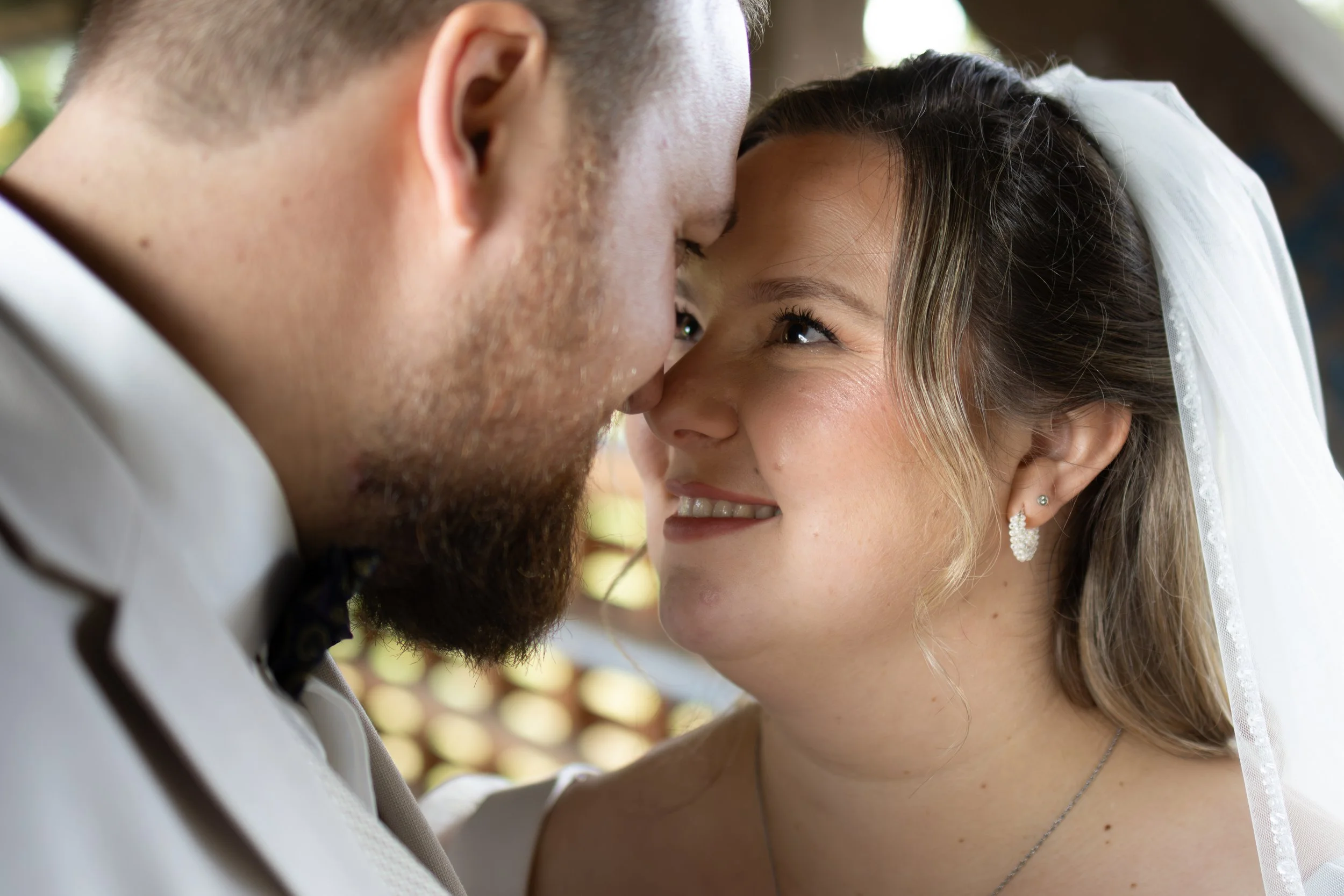 Ein Brautpaar bei seiner Hochzeit, das sich liebevoll berührt und anlächelt.