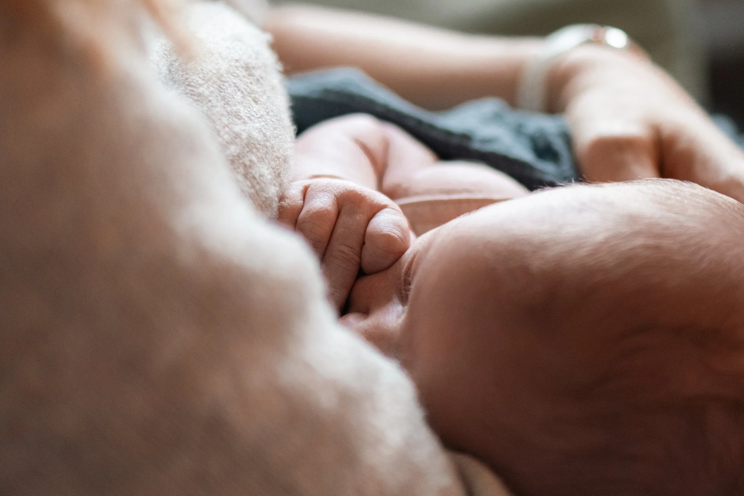 Nahaufnahme einer stillenden Mutter, die ihr Baby im Arm hält.