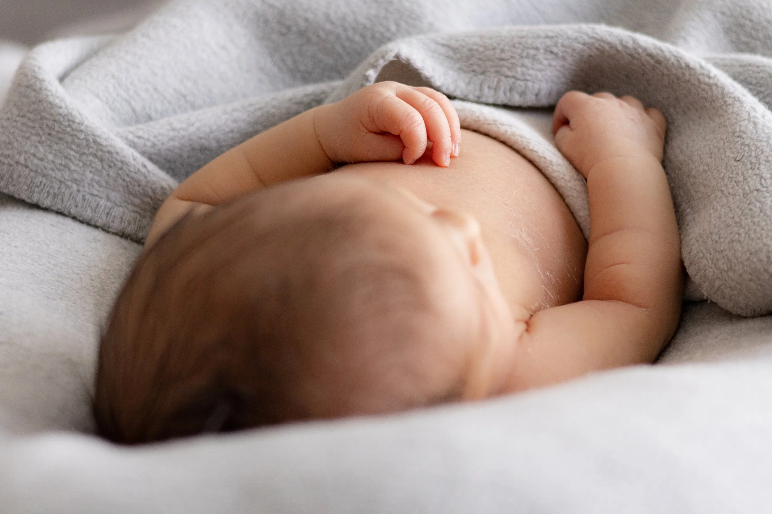 Nahaufnahme eines schlafenden Babys, das in eine Decke eingekuschelt ist.