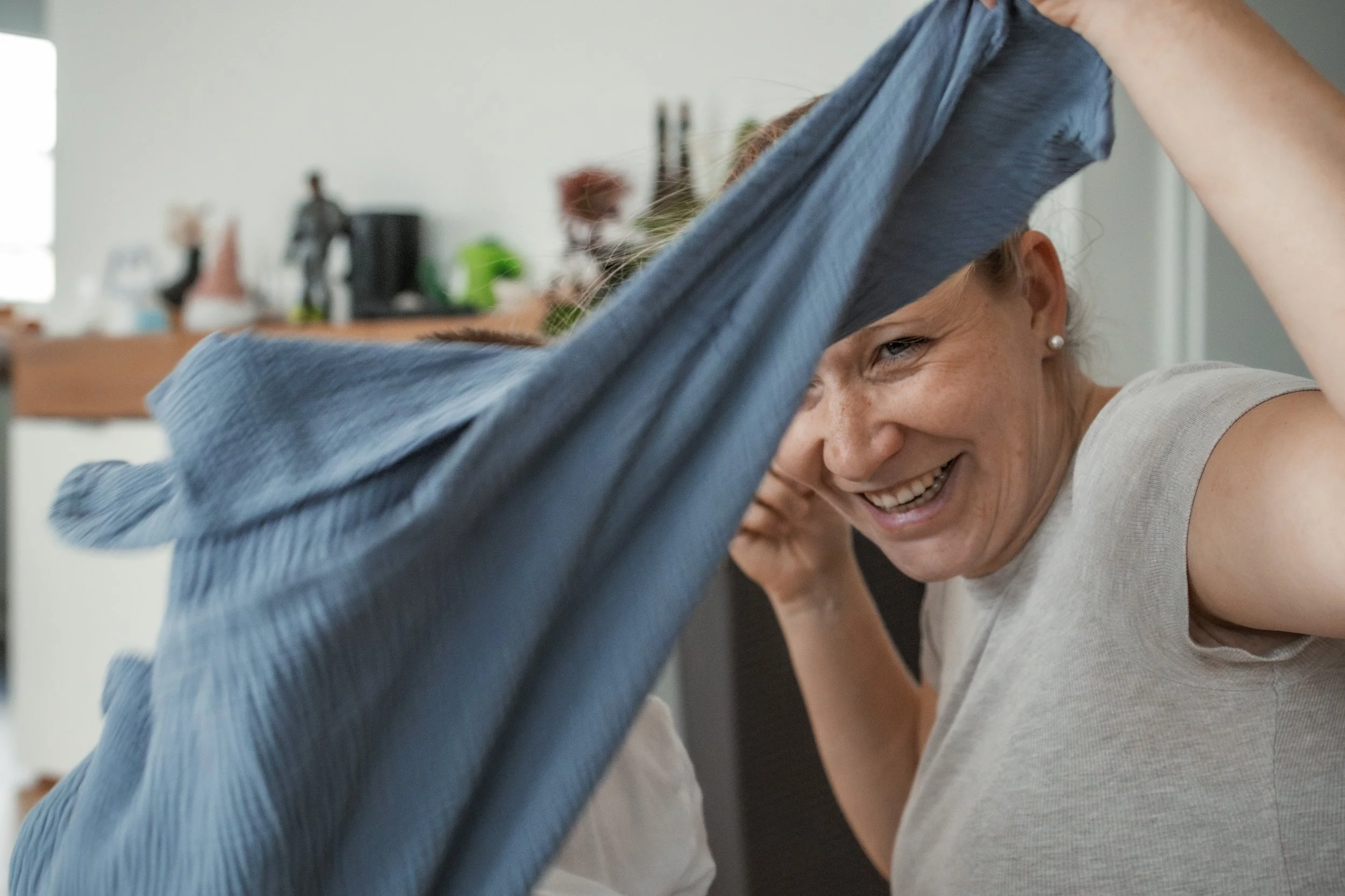 Lächelnde Frau beim Anziehen ihrer Kleidung in einem Haushalt.