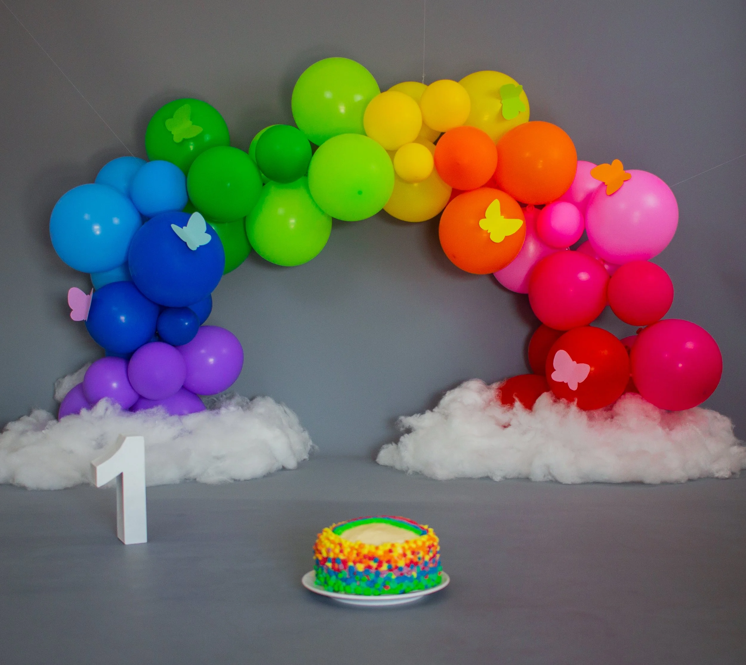 Dekoration mit bunten Ballons in Regenbogenfarben, Angelhaken und ein Kuchen, vermutlich für einen Kindergeburtstag.