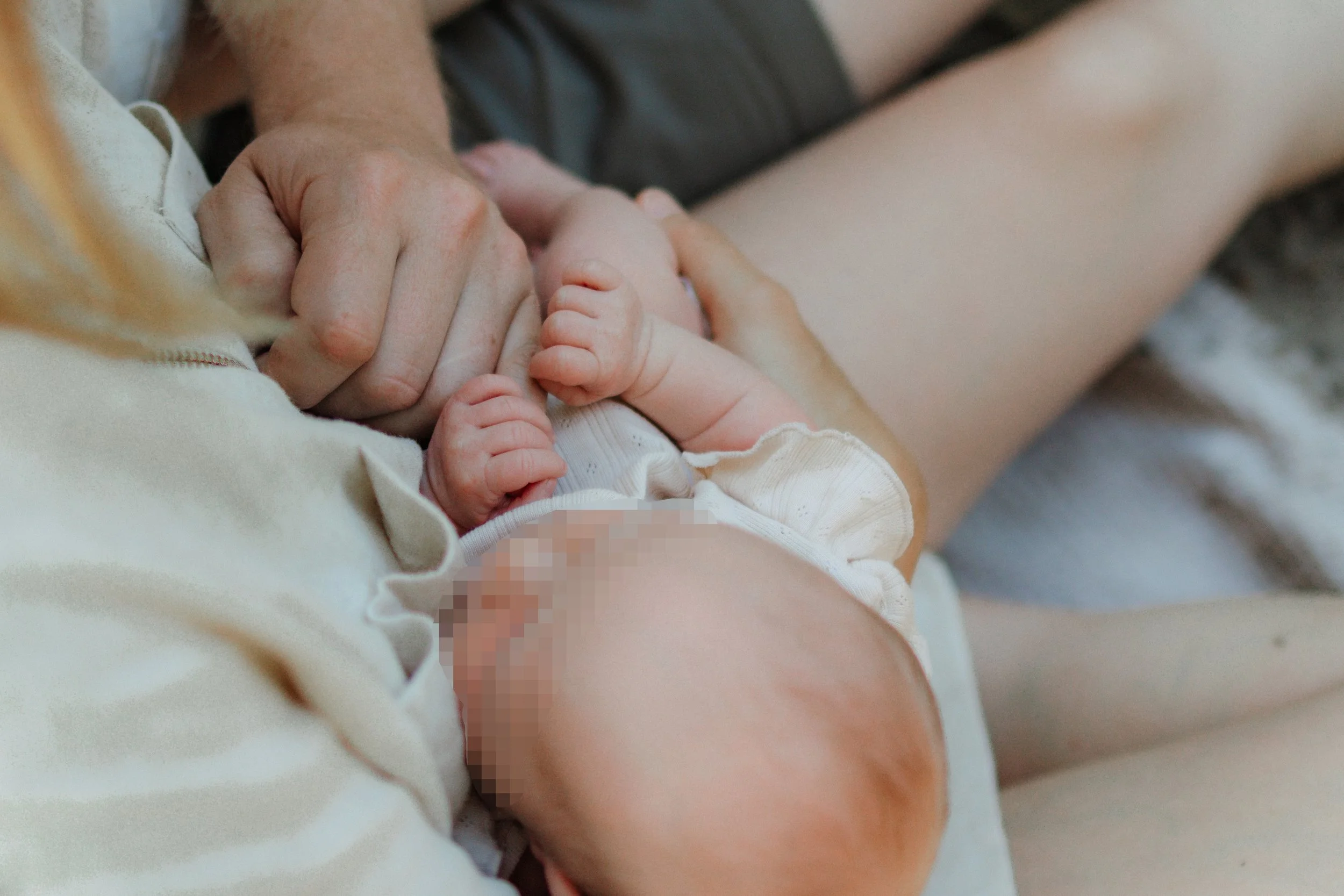 Ein neugeborenes Baby, das von einer Person gehalten wird, im Nahaufnahme, Pixeleffekt auf den Kopf des Babys, in einer intimen Nähe aufgenommen.