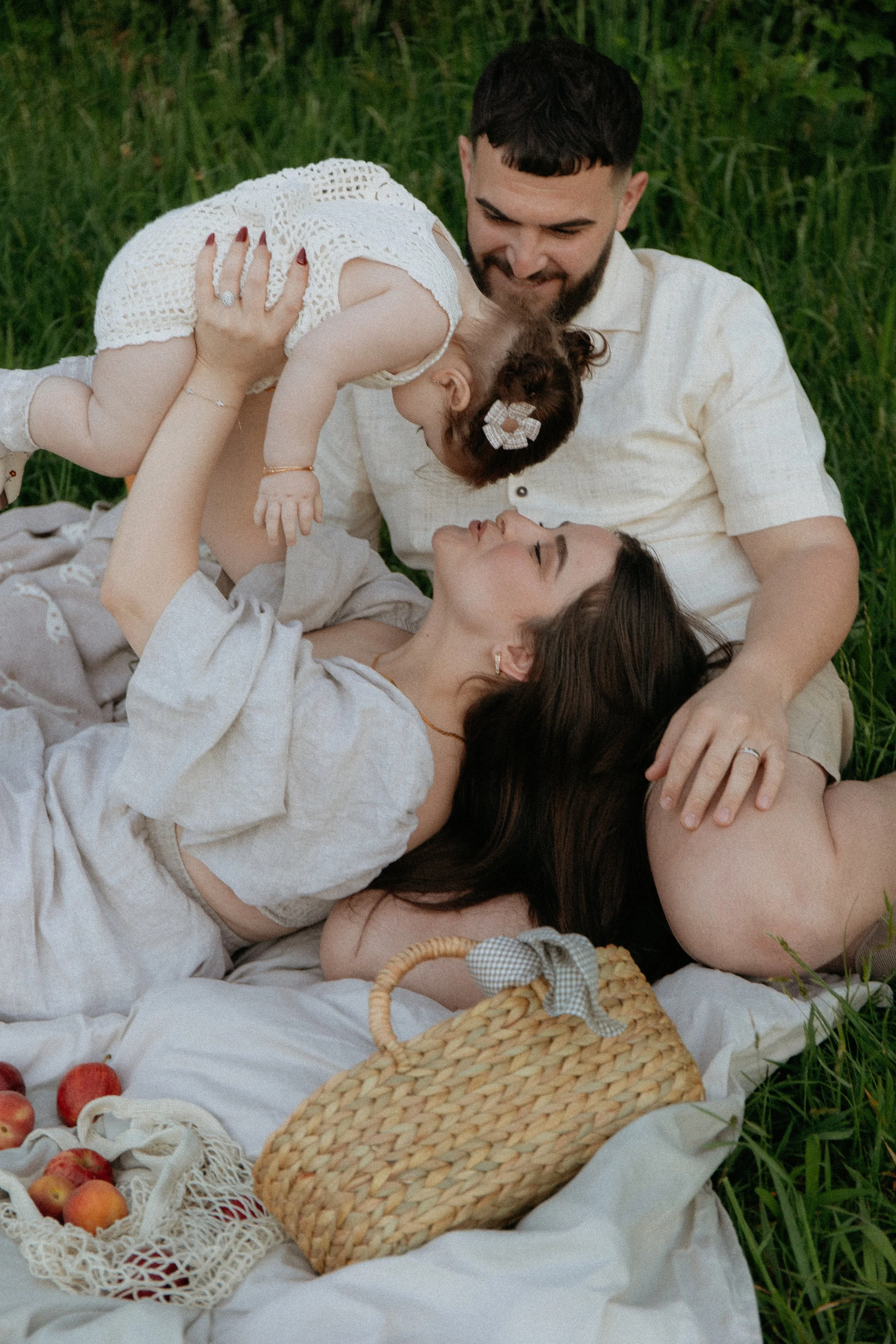 Family of 3 with my lifting baby up. Sitting on a picnic rug in Melbourne