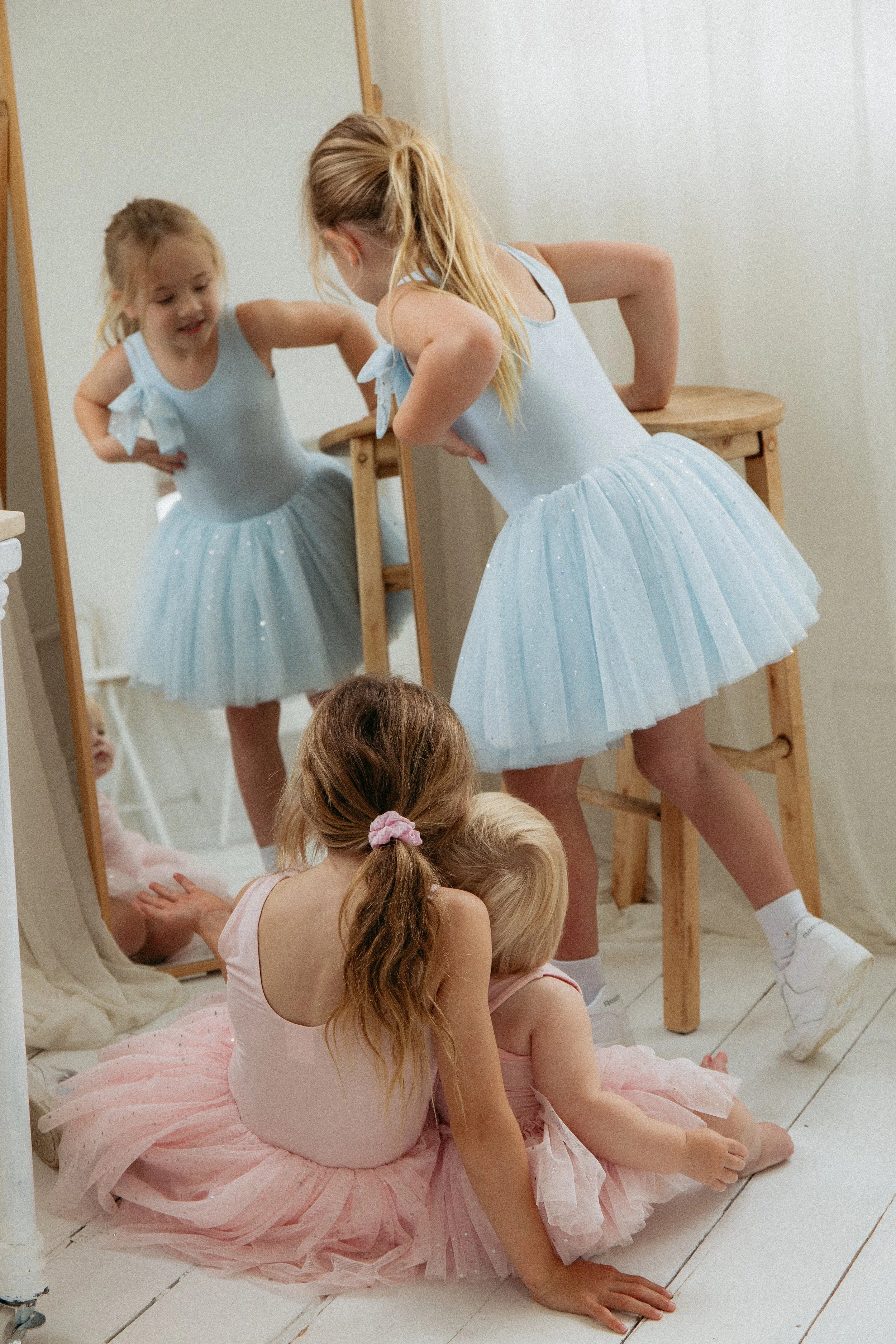3 sisters in tutus in front of a mirror