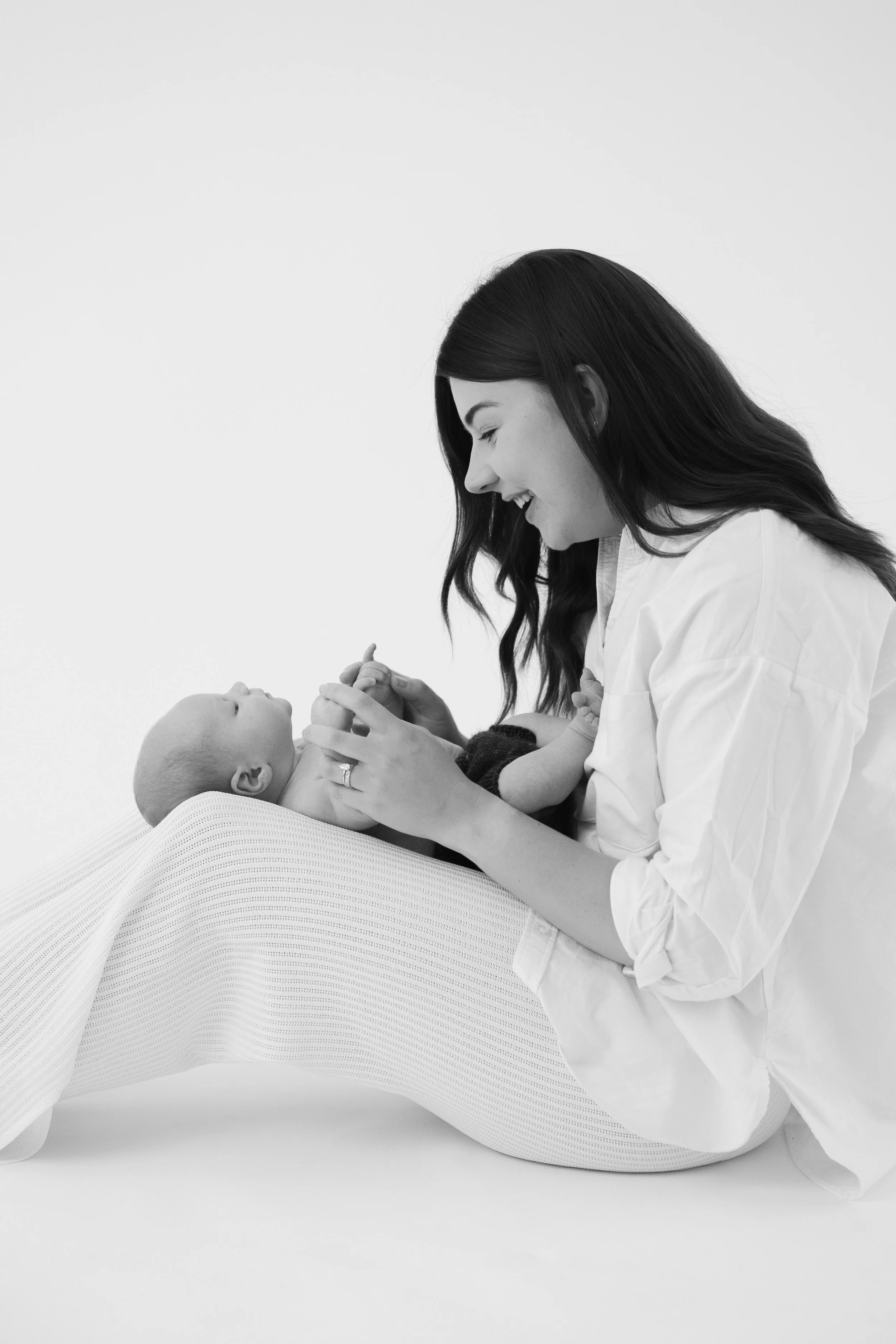 Black and white photo of mum holding her newborn on her lap