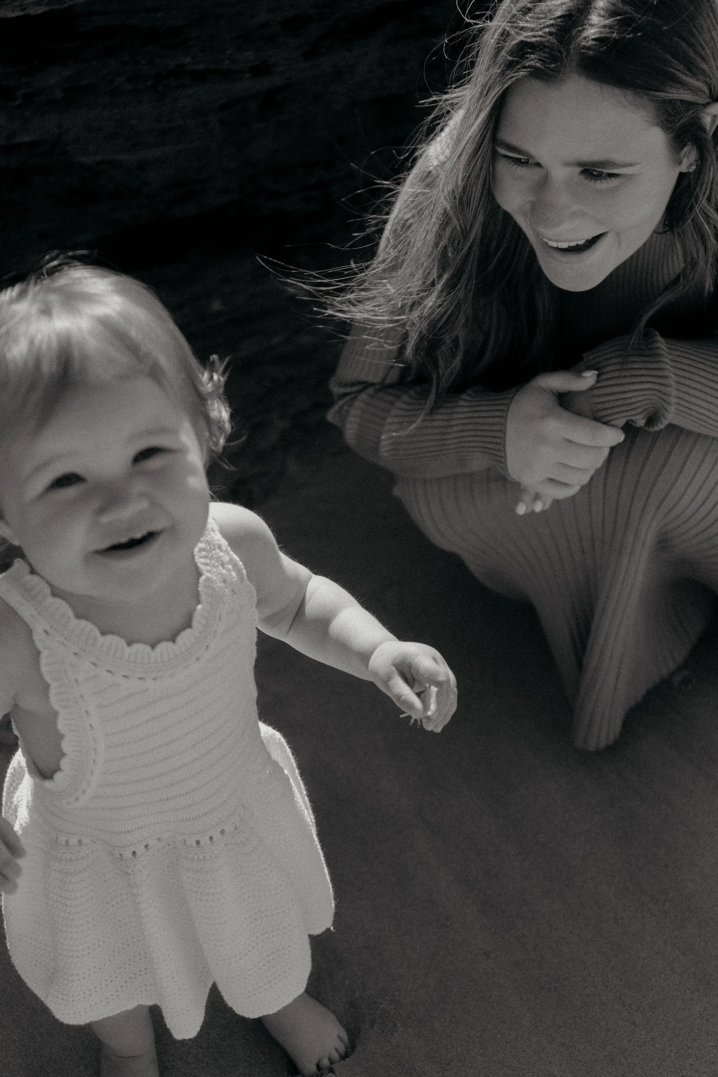 Mum looking at her daughter. Daughter looking at the camera on a beach