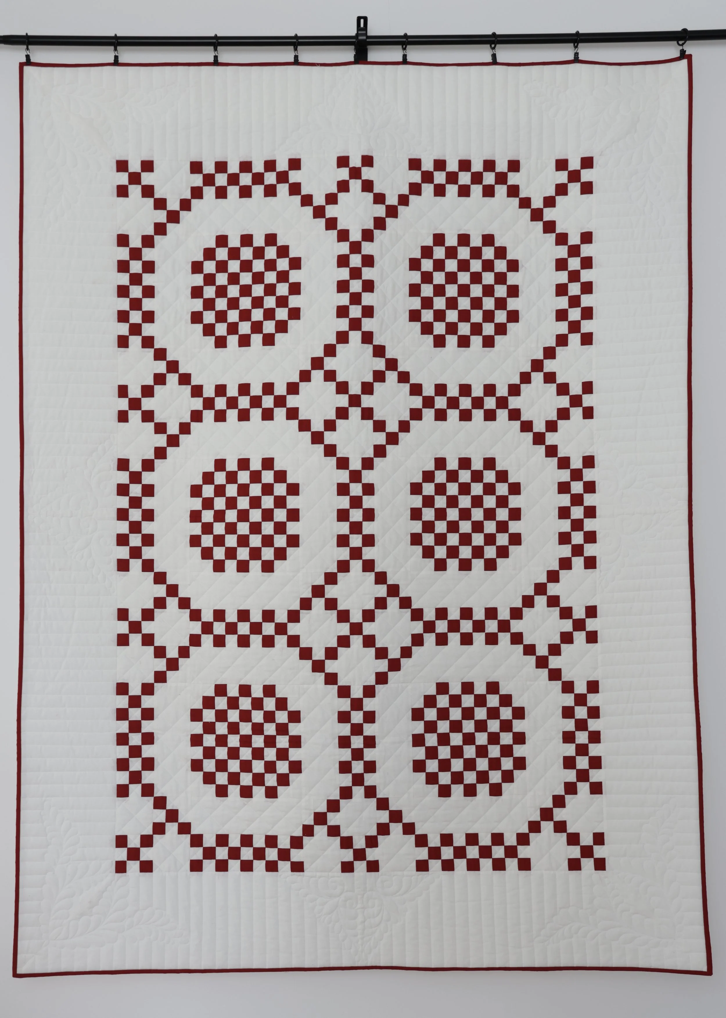 A quilt with a red and white geometric pattern.