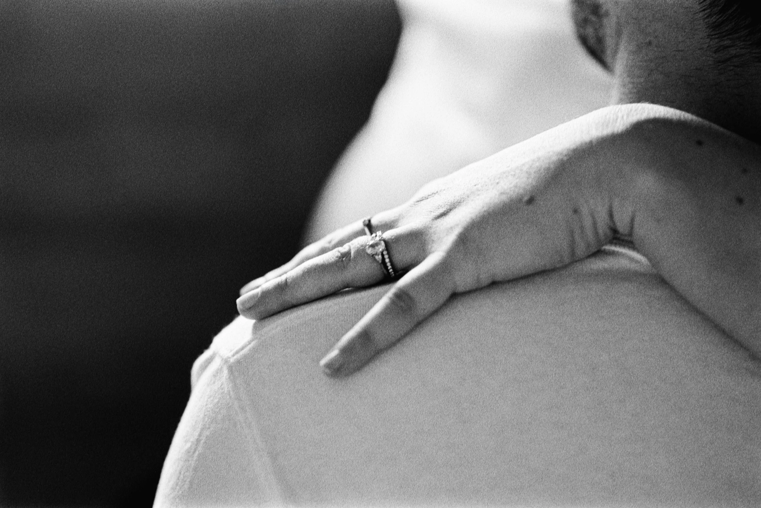 Une main avec une bague de mariage posée sur l'épaule d'une autre personne à l'argentique dans les Yvelines.