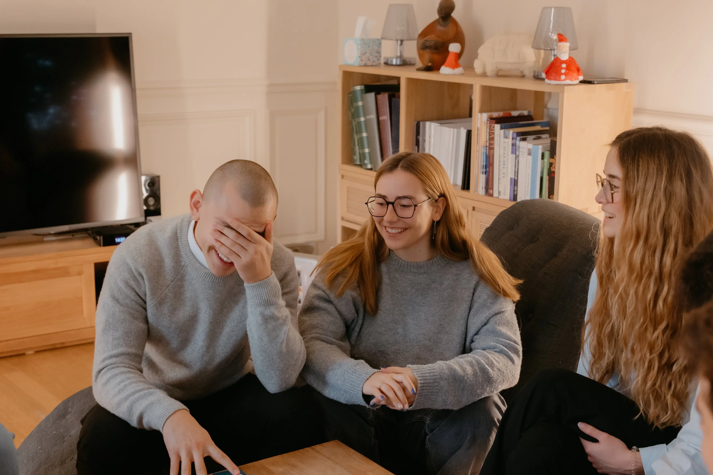 Une famille des Yvelines riant et échangeant lors d'un jeu de société ou d'une fête à la maison des Yvelines.