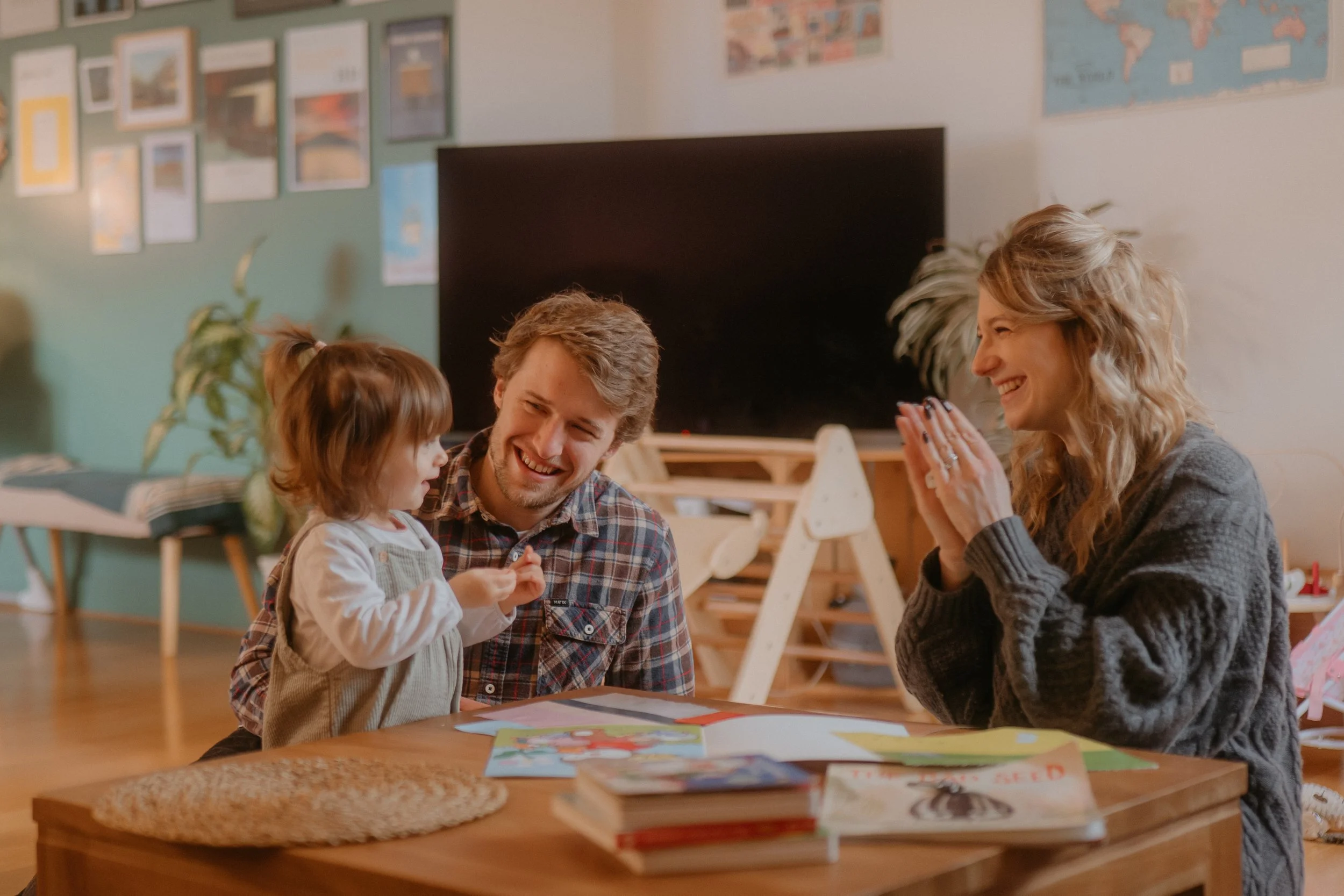 Une famille réunie autour d'une table, souriant et appréciant un moment de partage, avec des livres et des coloriages dessus.