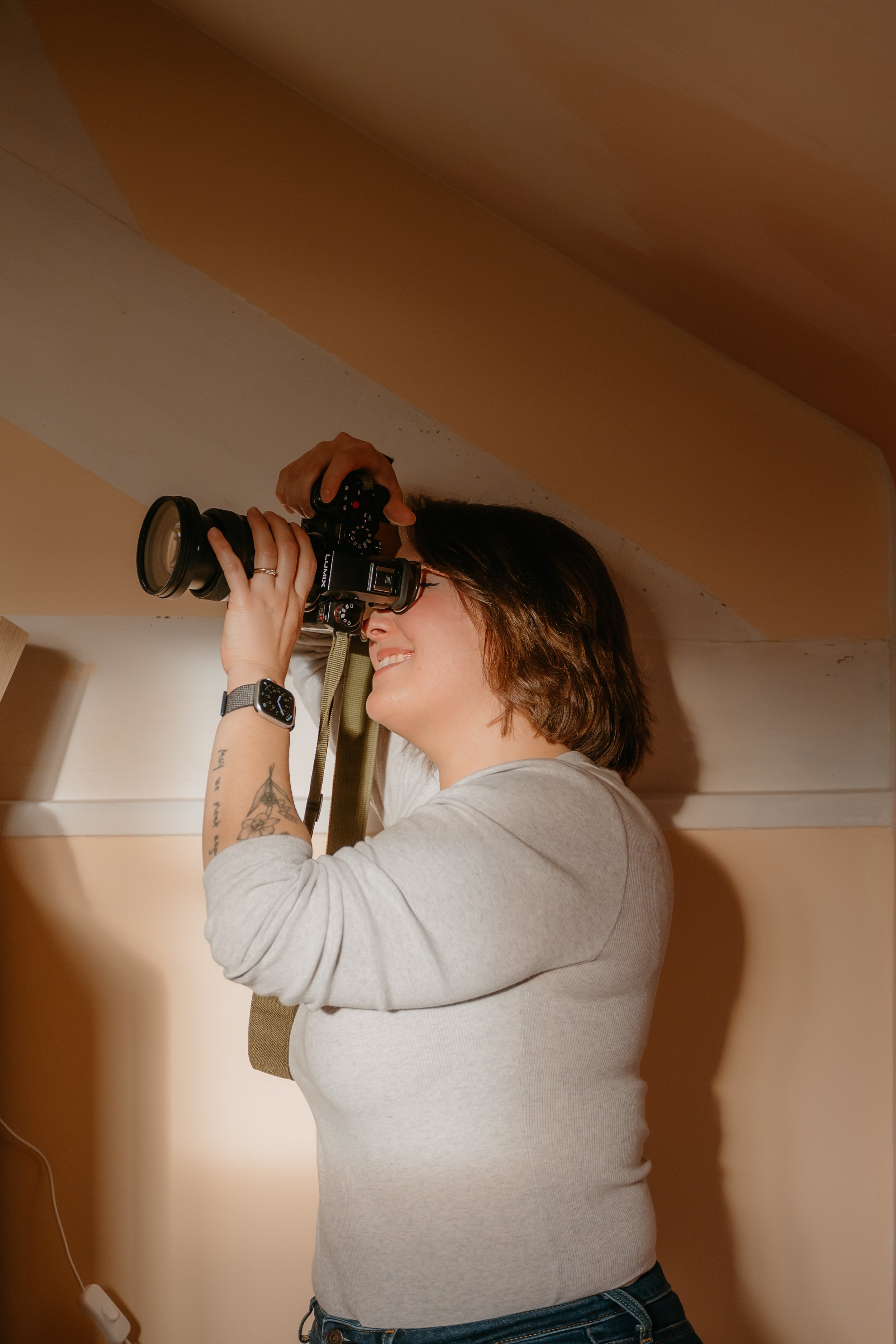 Une photographe famille souriante prend une photo avec un appareil photo numérique dans une pièce dans les Yvelines.