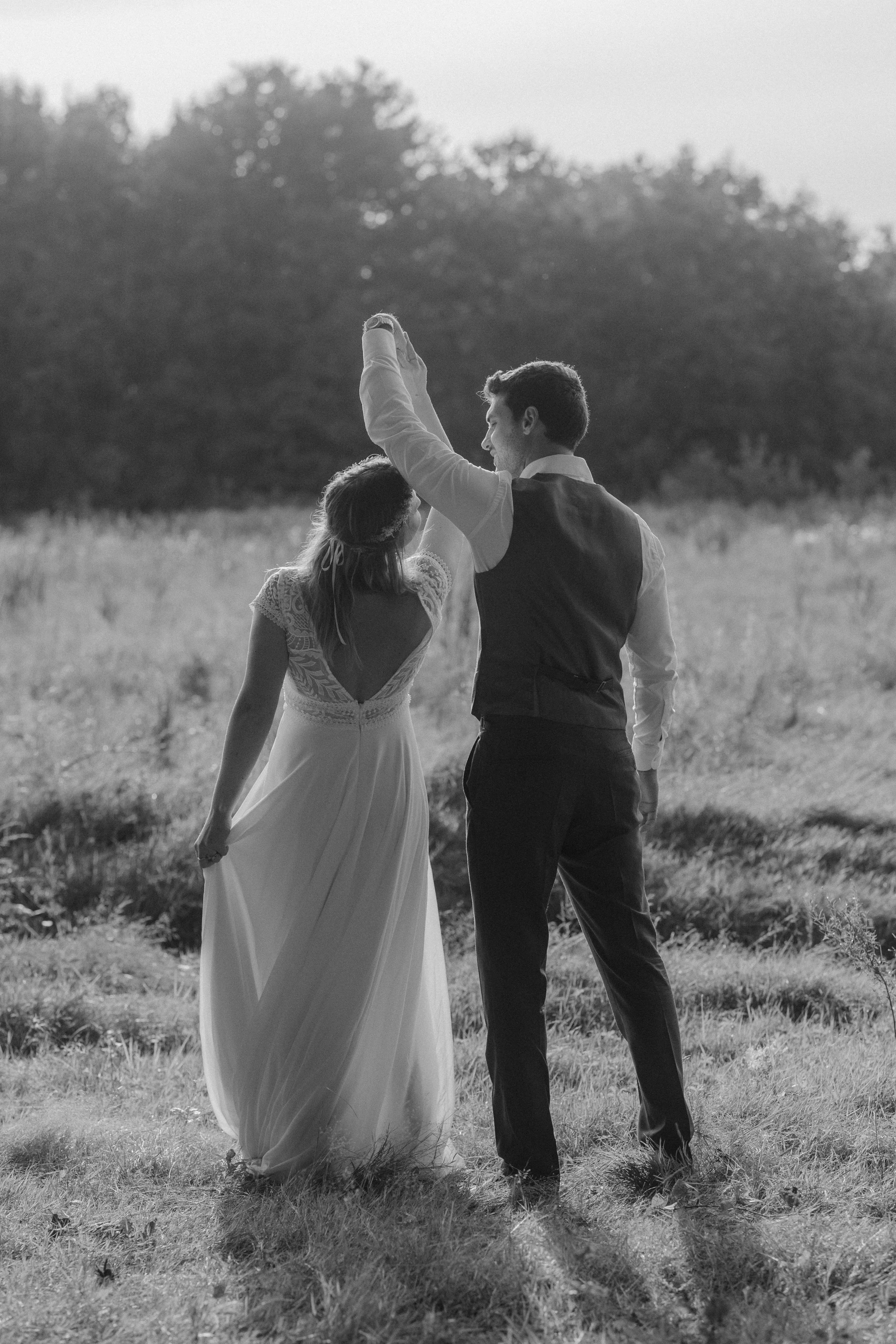 Un couple de jeune marié qui danse dans un champ des Yvelines en plein air, image en noir et blanc.