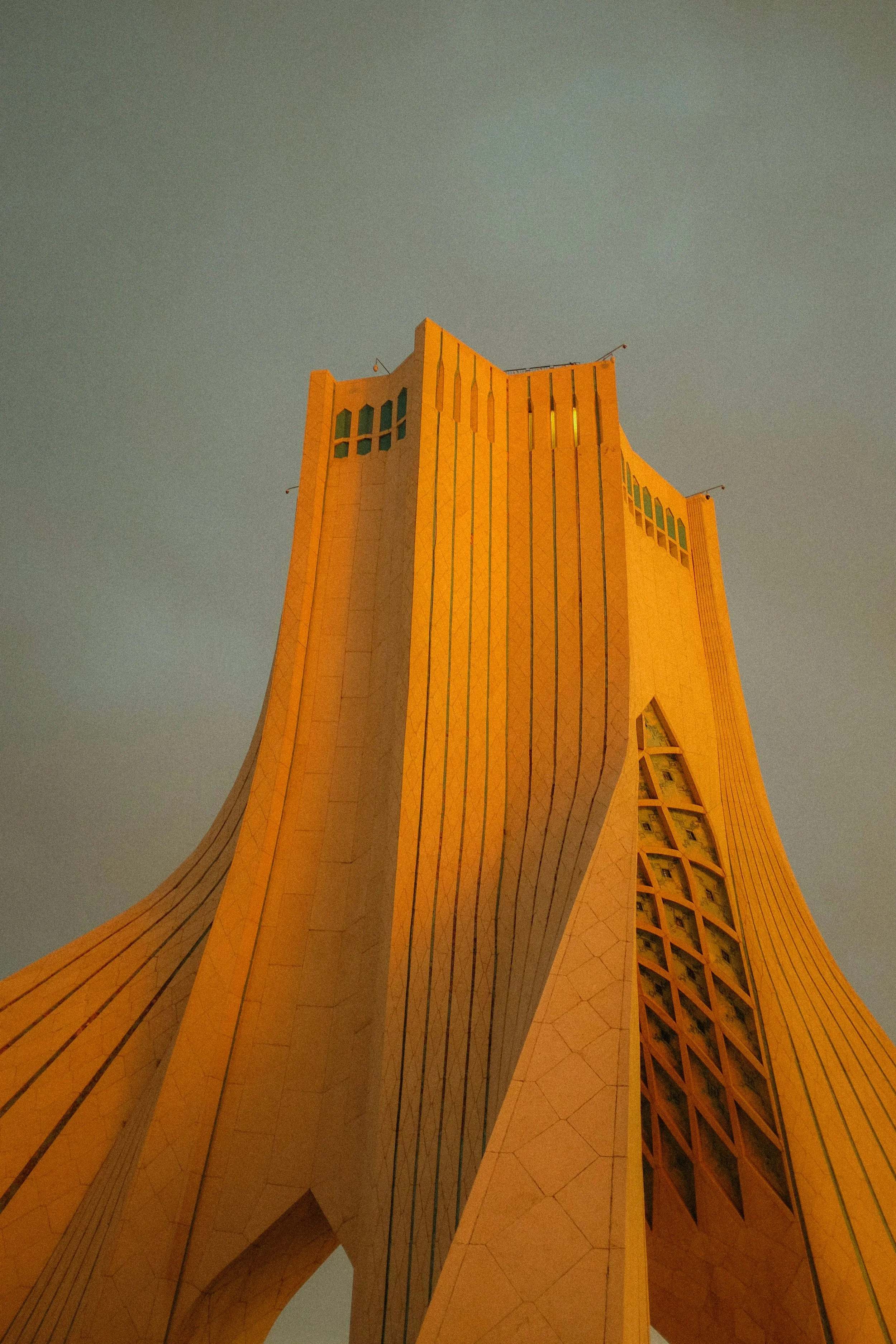 Tall, modern skyscraper with sharp angles and a yellow-orange facade