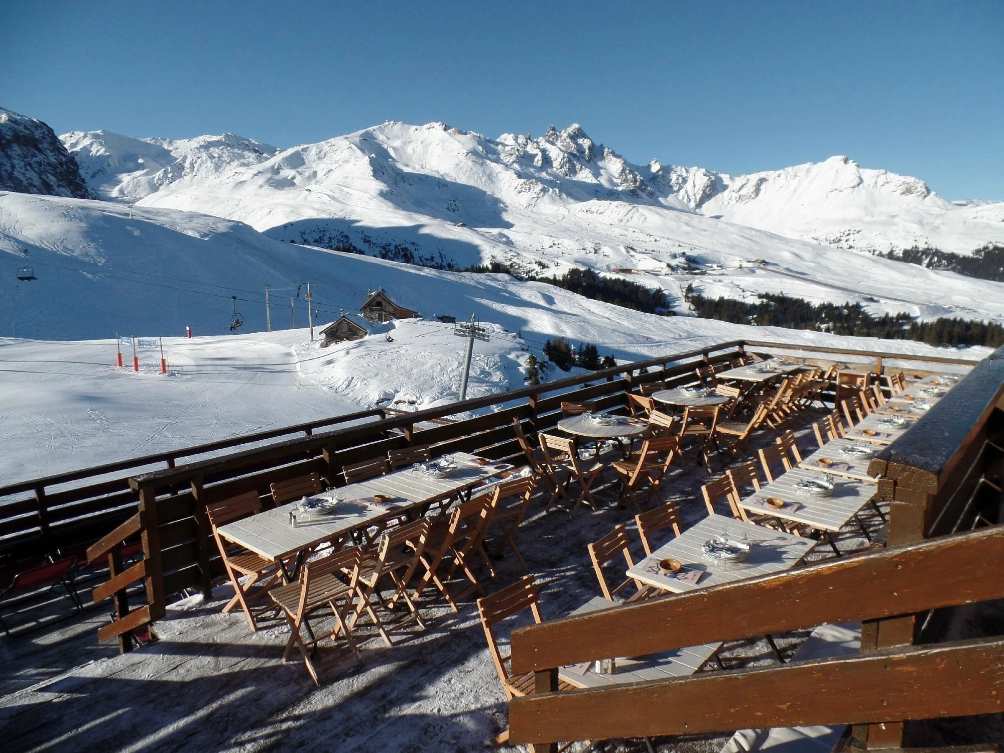 Le Bel Air, Courchevel terrace on a sunny day. Watch skiers and snowboarders go by as you enjoy a drink on the warm terrace.