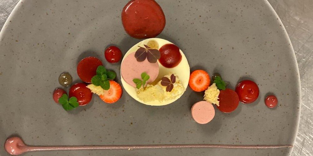 A gloriously vibrant looking pudding consisting of strawberries, gels and what looks to be a lovely white chocolate cheesecake.