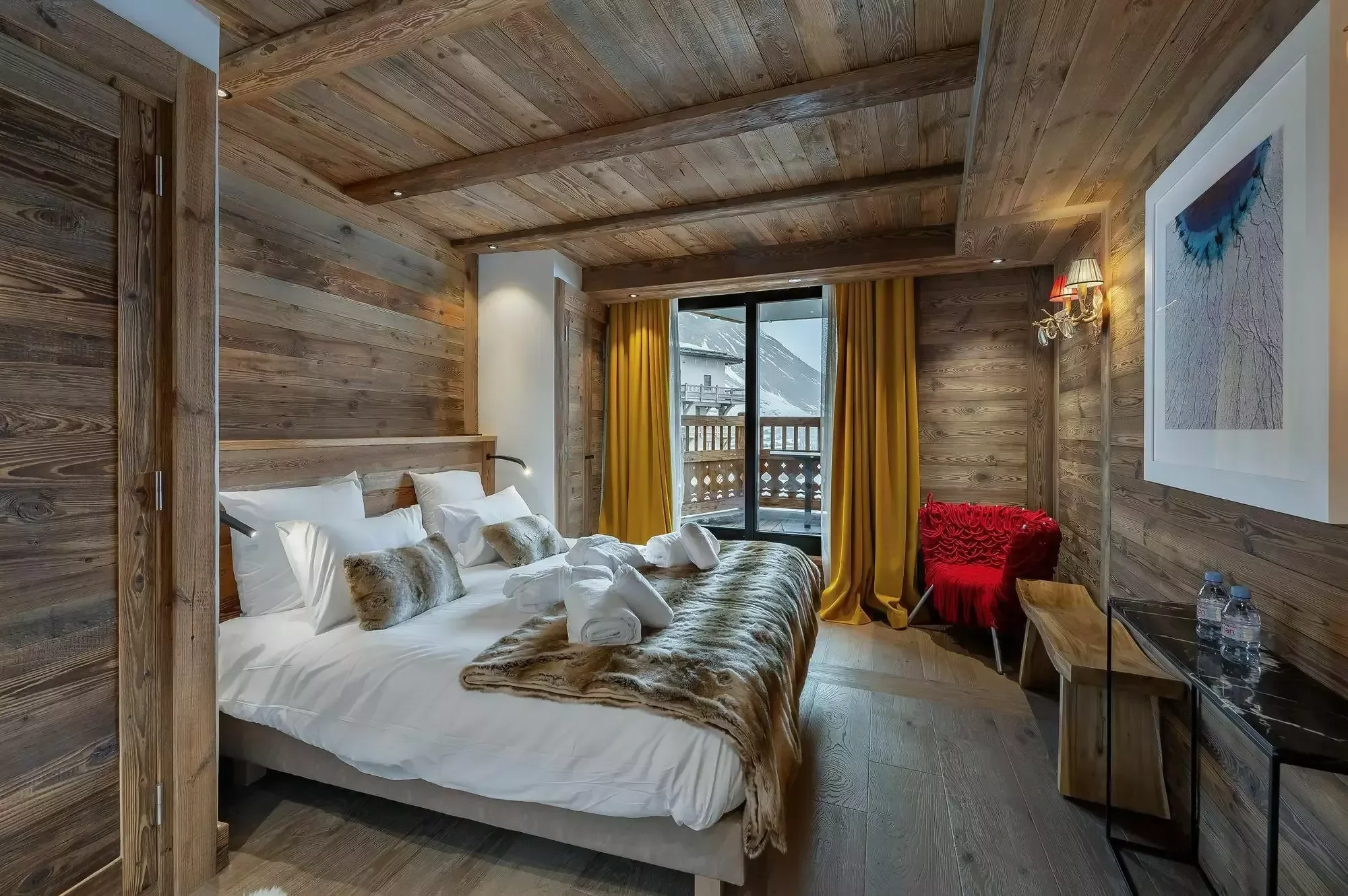 Plush double bedroom in  La Face Apartment. Lovely wooden interior, soft warm lighting and large draped curtains.