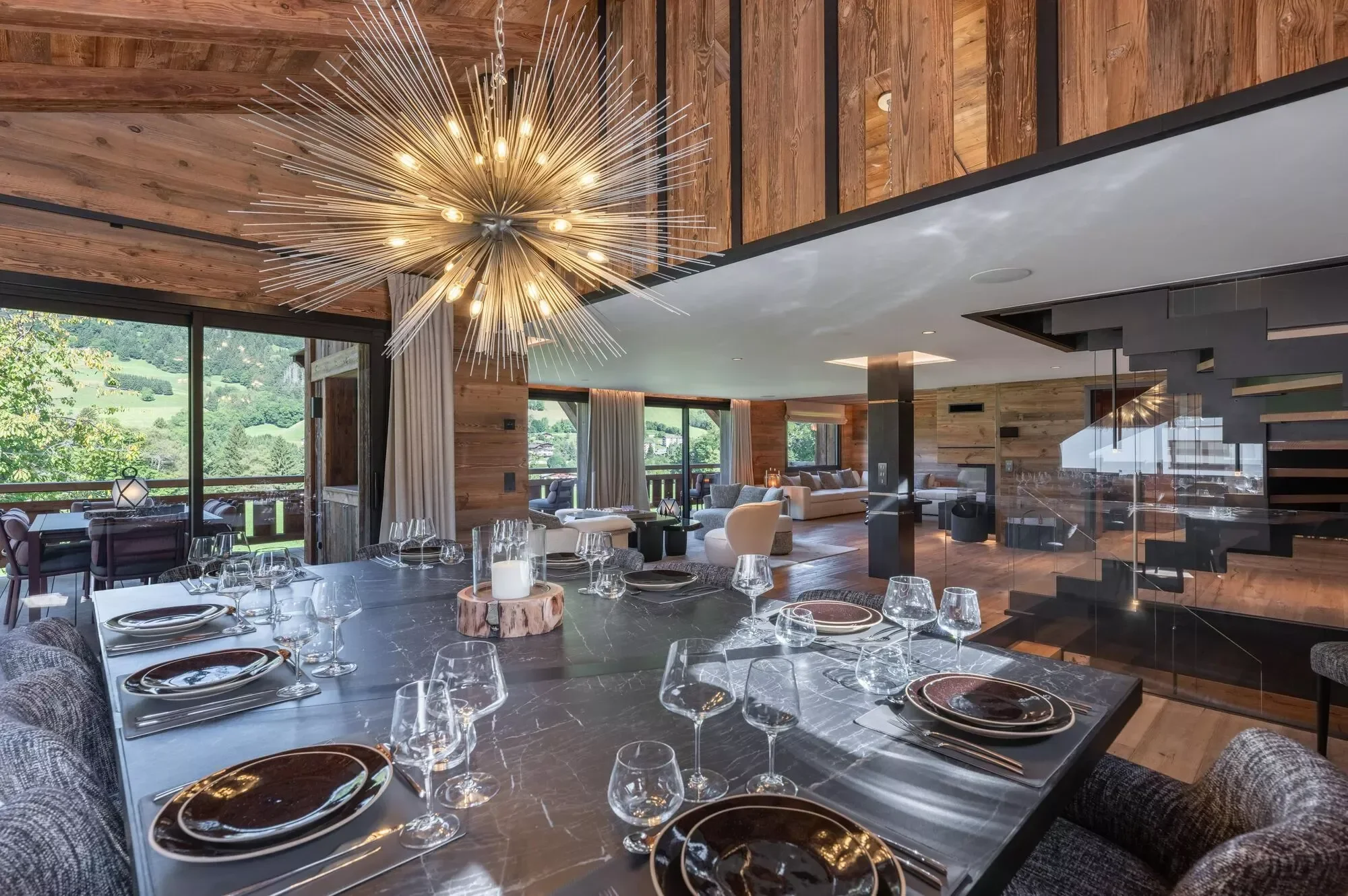Open plan dining area with striking chandelier above the dining table. All set for dinner, this is a large and open space.
