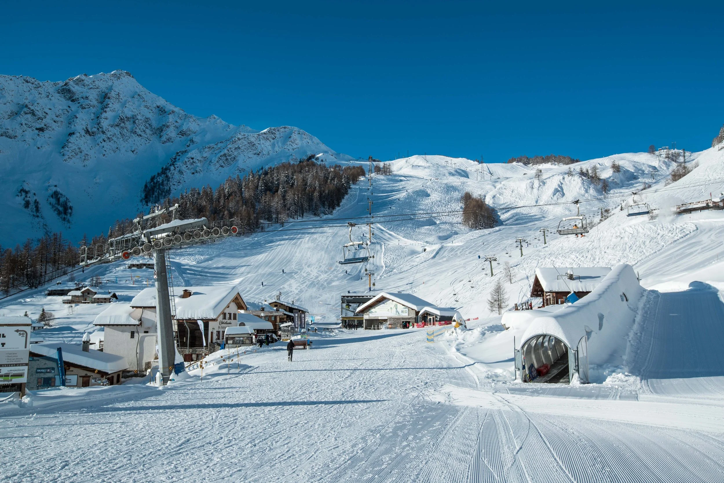 Courmayeur Mountain Mid Station with perfect blue sky conditions and ski piste around.