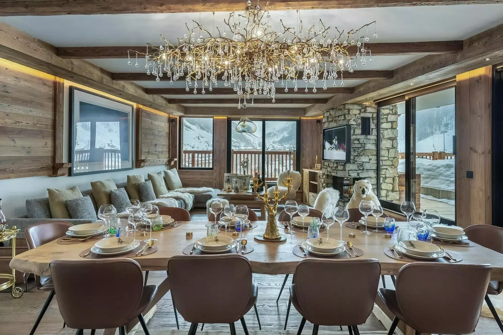 Beautifully laid dining table for 10. A crystal chandelier overhead creates a luxury setting and the lounge in the background brings everyone together.