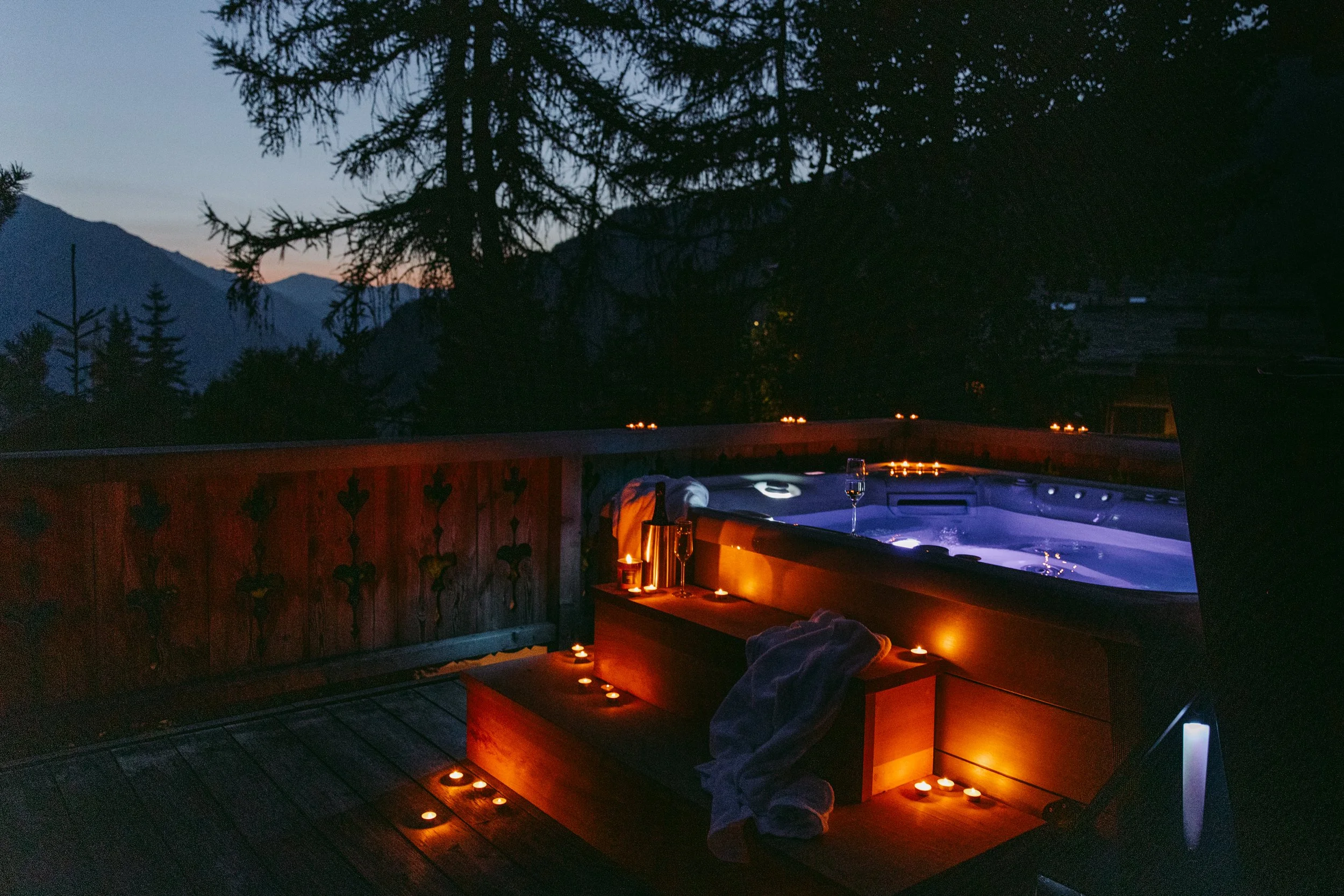 Night time hot tub outside of a catered chalet with champagne