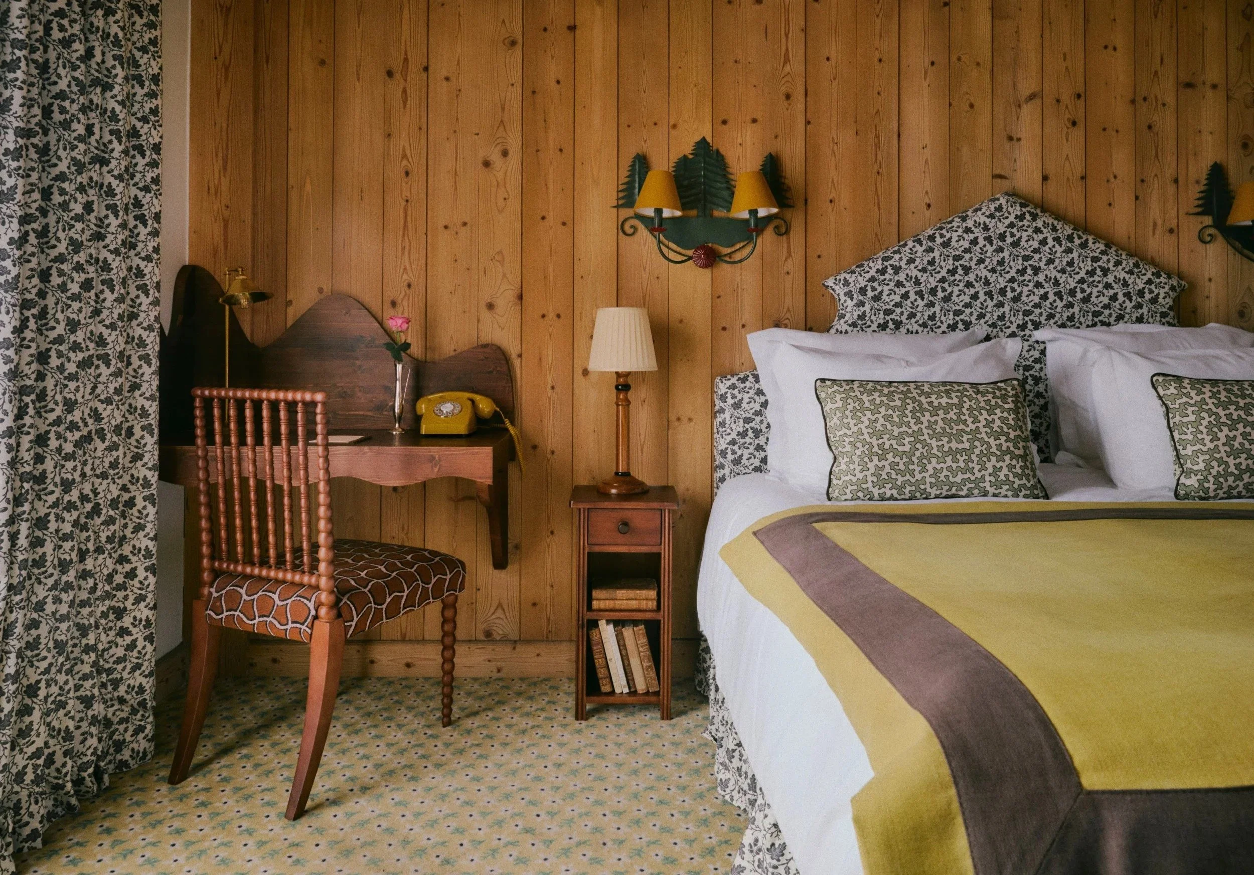 A classic Savoyarde style bedroom in the Saint-George hotel. Yellow bedding, alpine walls and office desk with chair.