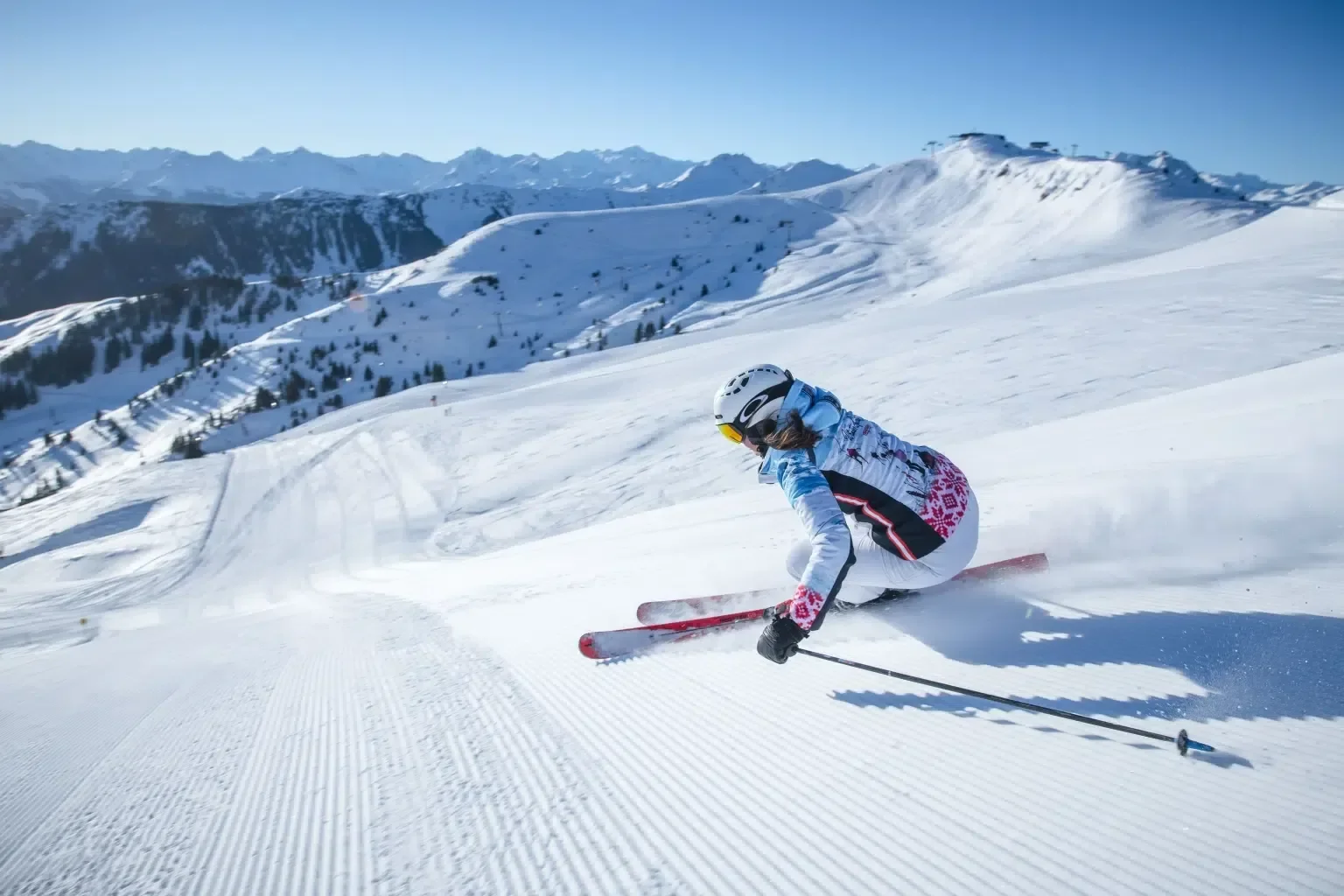 Downhill skiing in Kitzbuhel. A lady with red skis, white, pink and blue jacket.