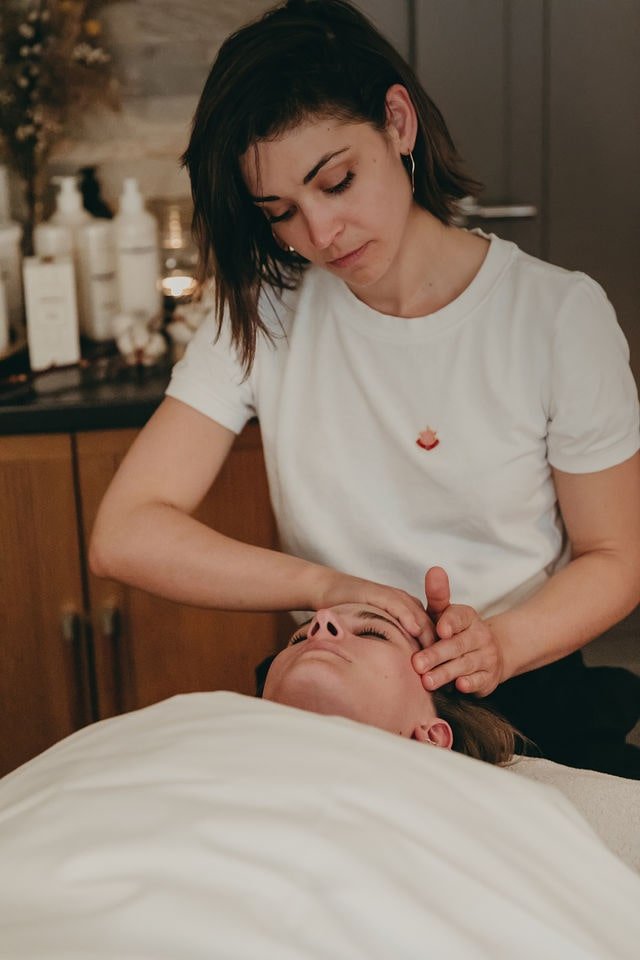 A woman receiving a facial treatment from a skincare professional in a spa or clinic setting.