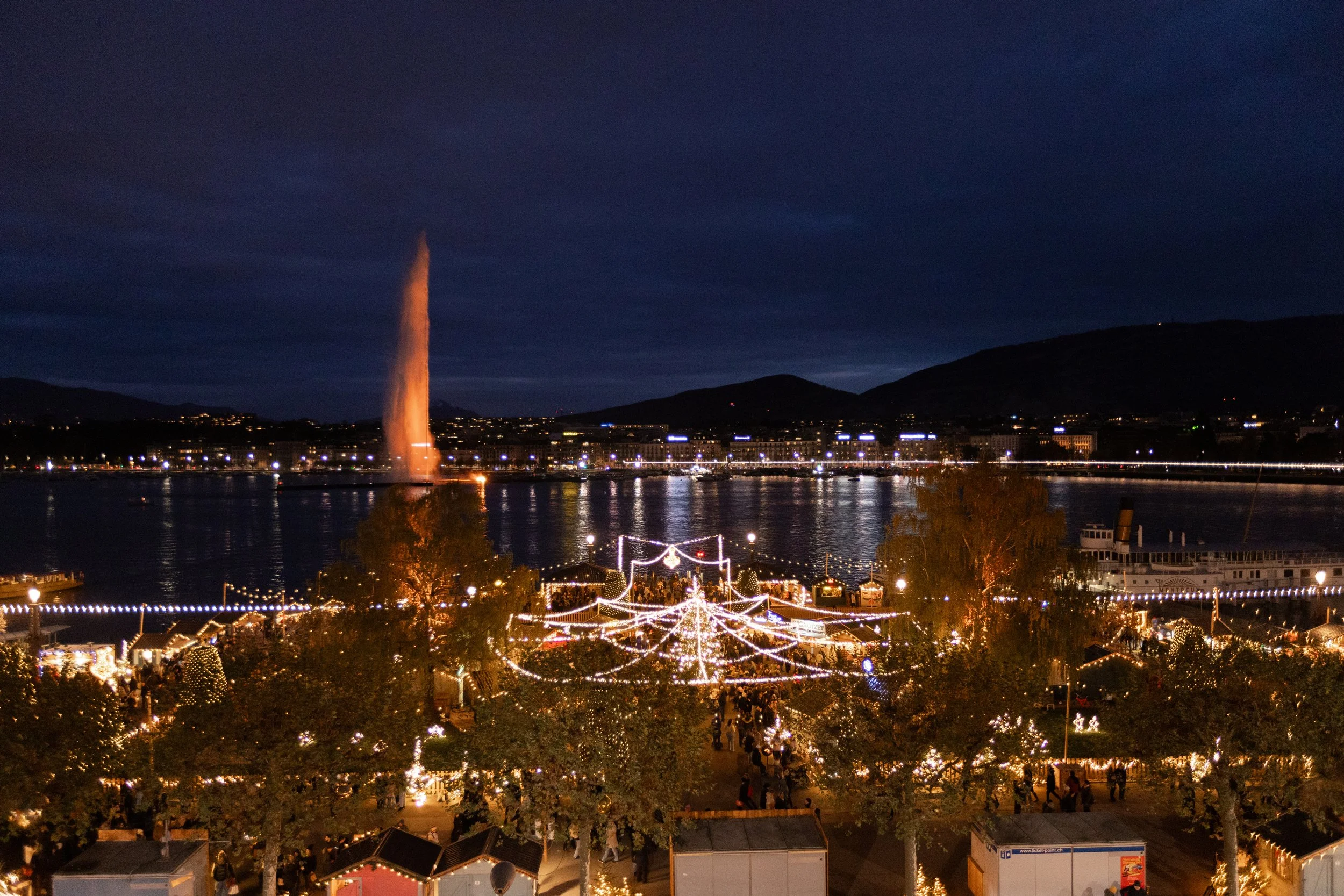 Marché de Noël in Geneva. Fairy lights at Christmas light up the market overlooking the famous Geneva fountain.