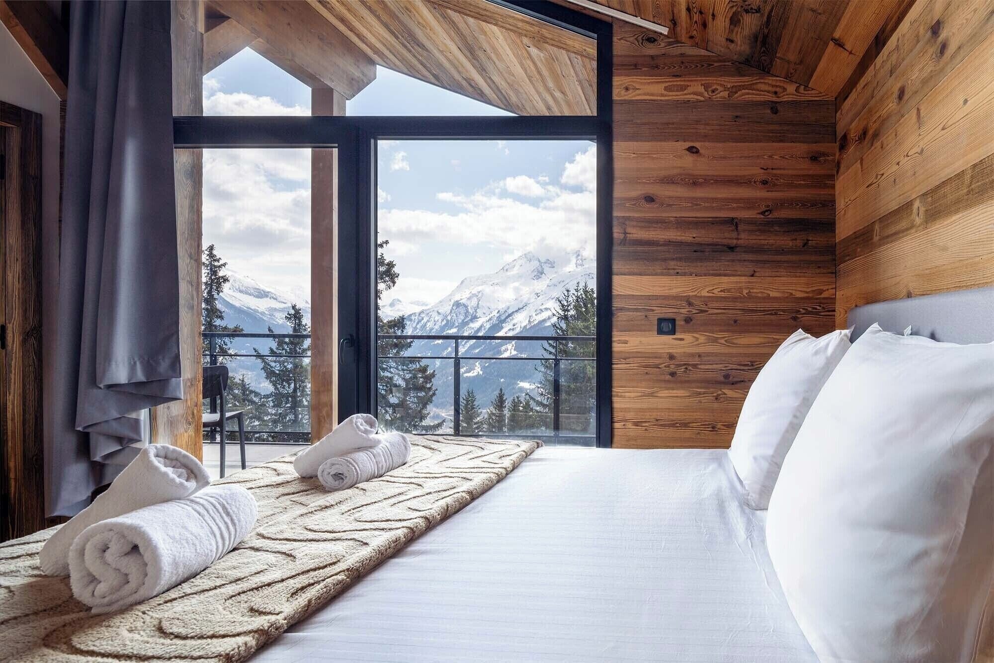 Double bed with mountain views, white sheets and love pine interior.