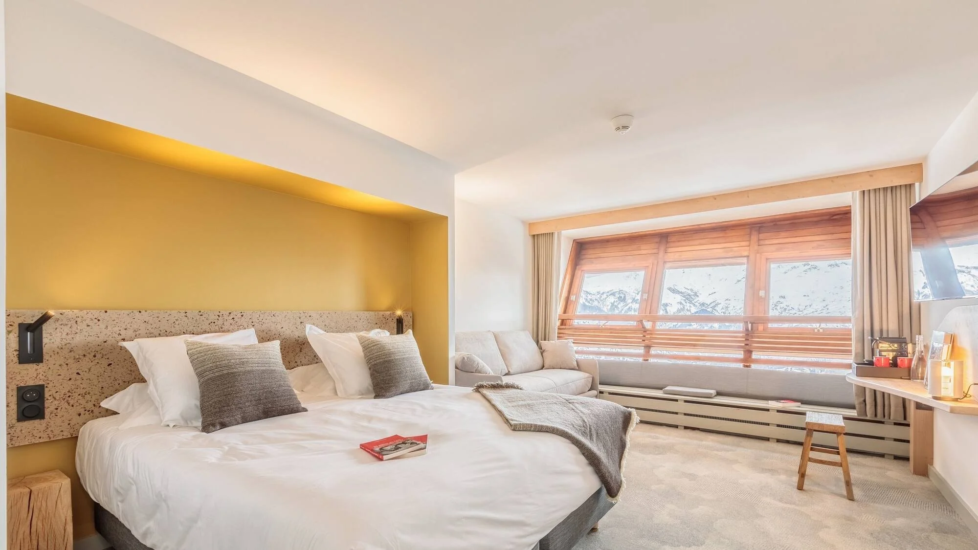 Double bedroom with headboard and mountain views beyond the sofa window.