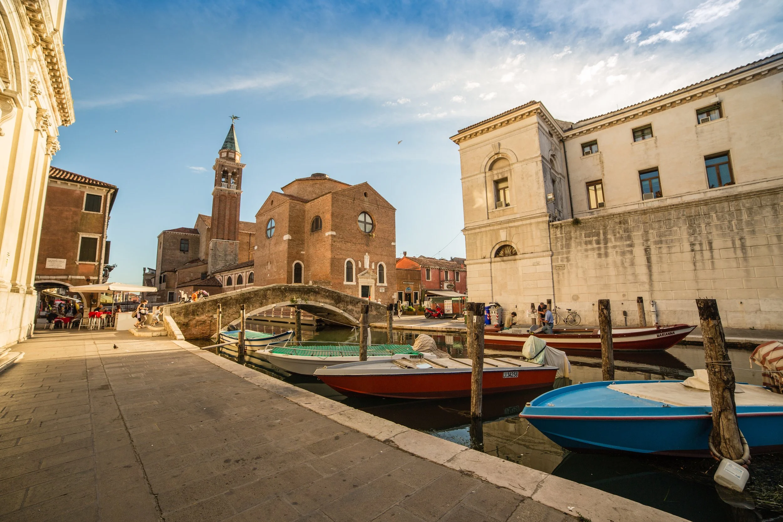 Venice canals on a sunny day with gondola boats passing by.