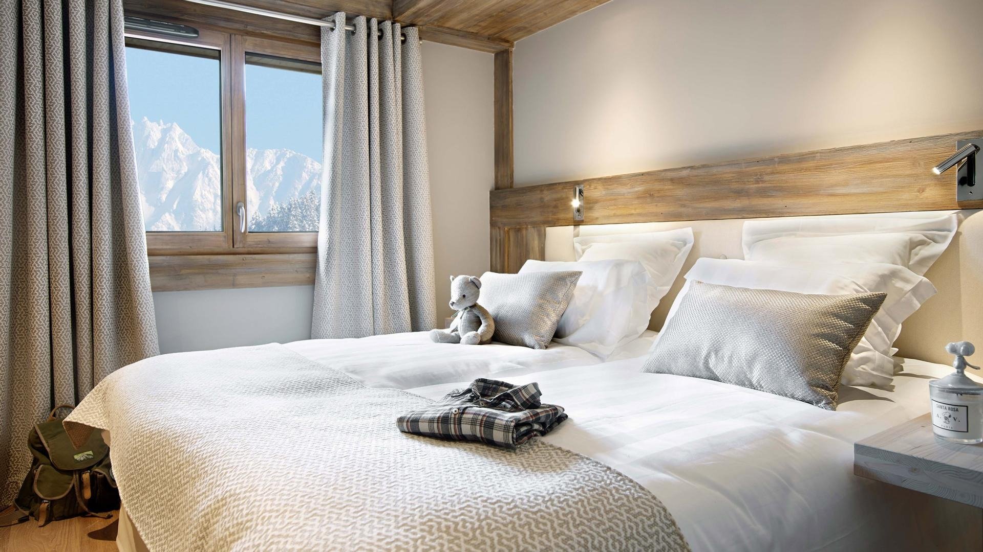 Plush double bedroom with light alpine décor and colours. Mountain views in a modern bedroom.