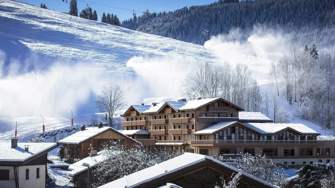 Image of slopeside hotel, Hotel Beauregard set in front of blasting snow cannons.