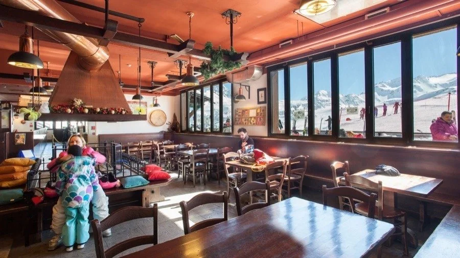 Restaurant with wooden interiors throughout and central fireplace.