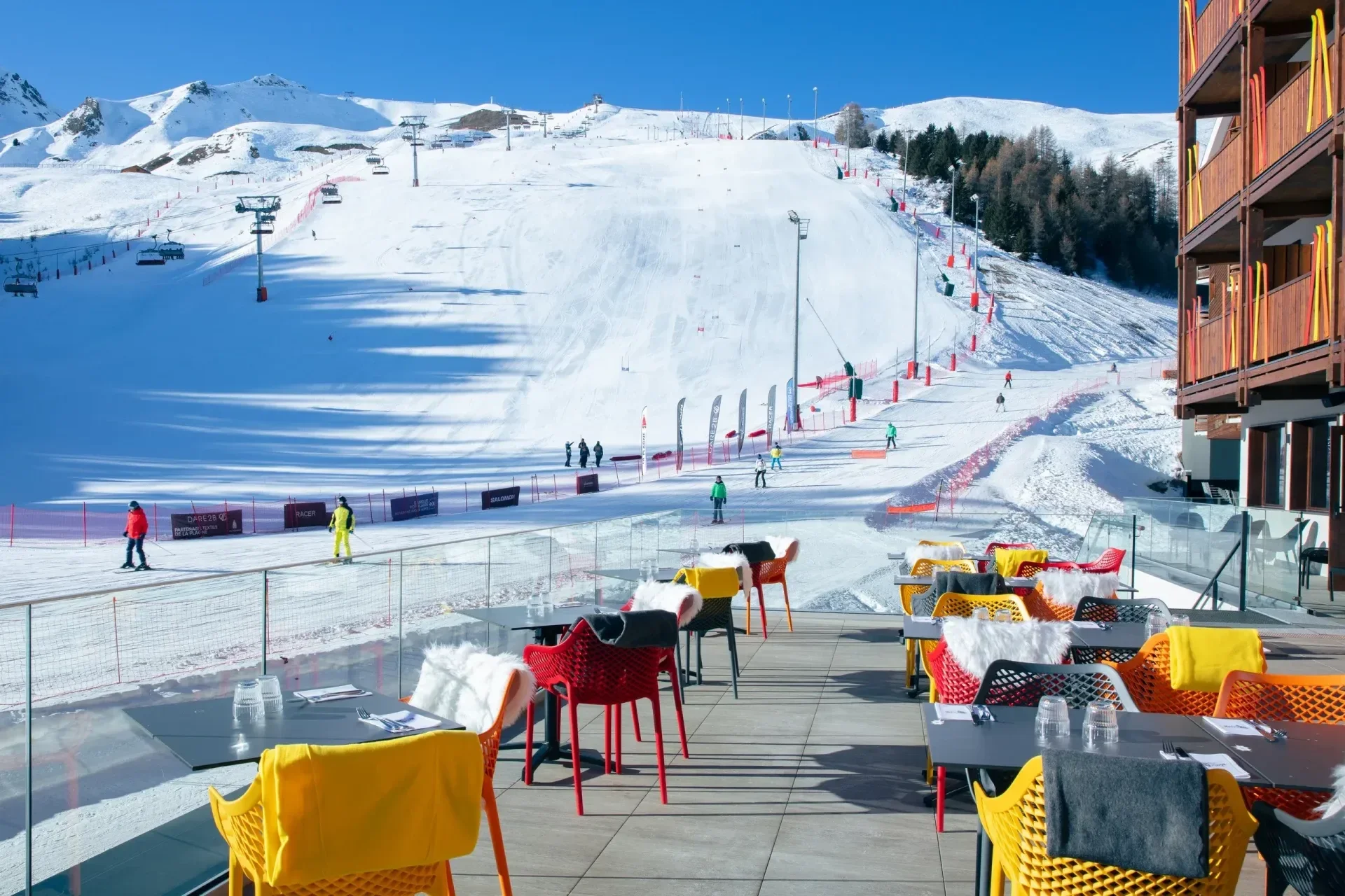 Alfresco dining on the side of the slopes at the Pop Alp Hotel in La Plagne. Colourful chairs overlooking the slopes and slalom course.