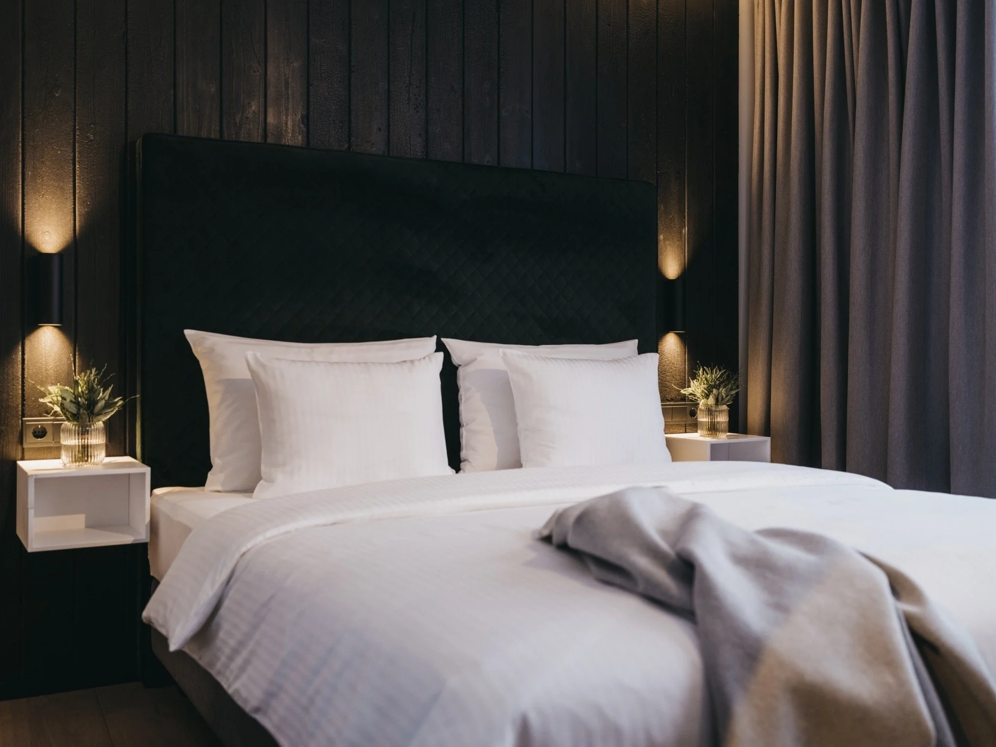 Plush double bedroom with white sheets, dark moody interior.