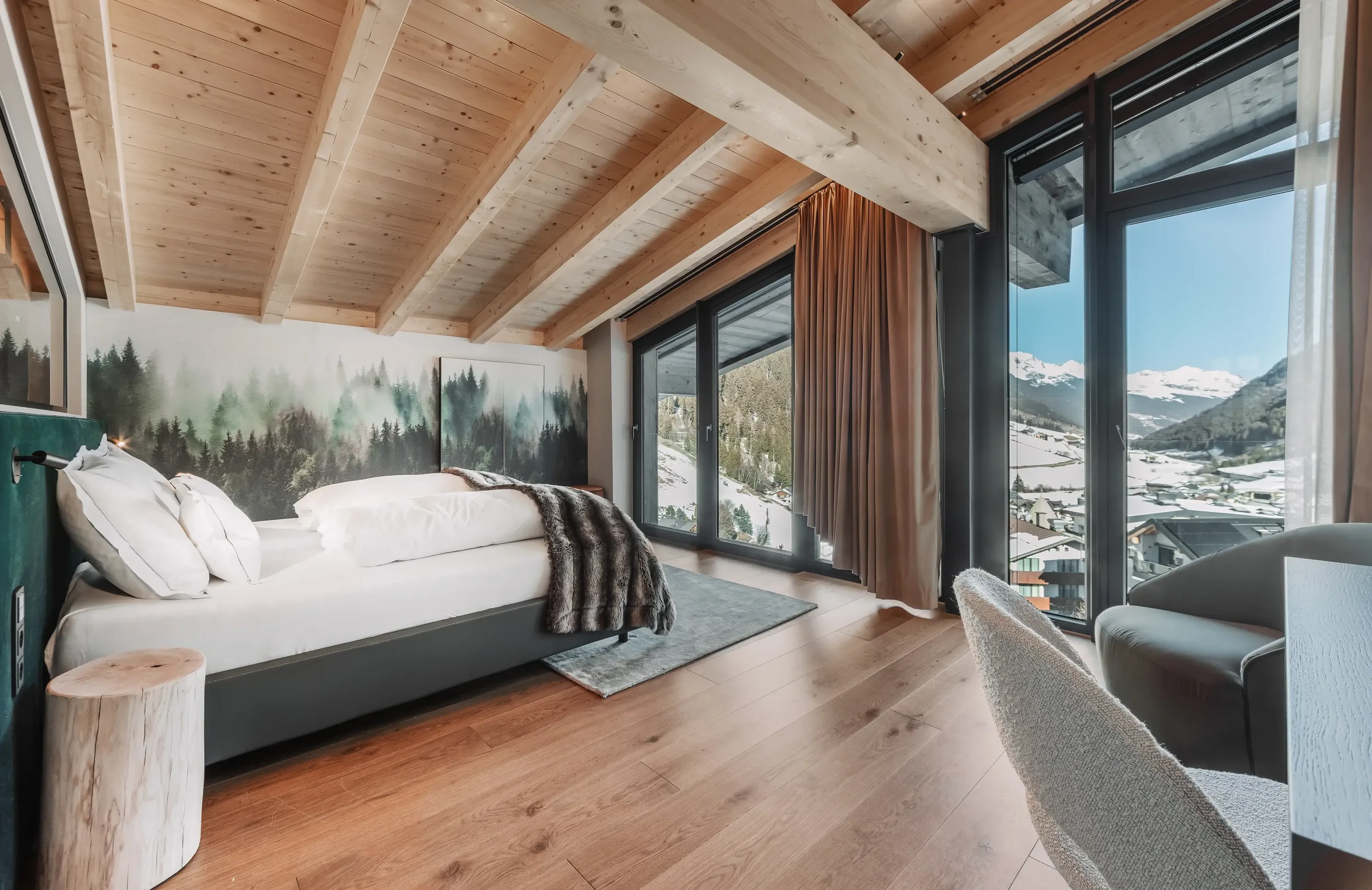 Large double bed with wooden interior offering beautiful views across the mountains and resort of Ischgl